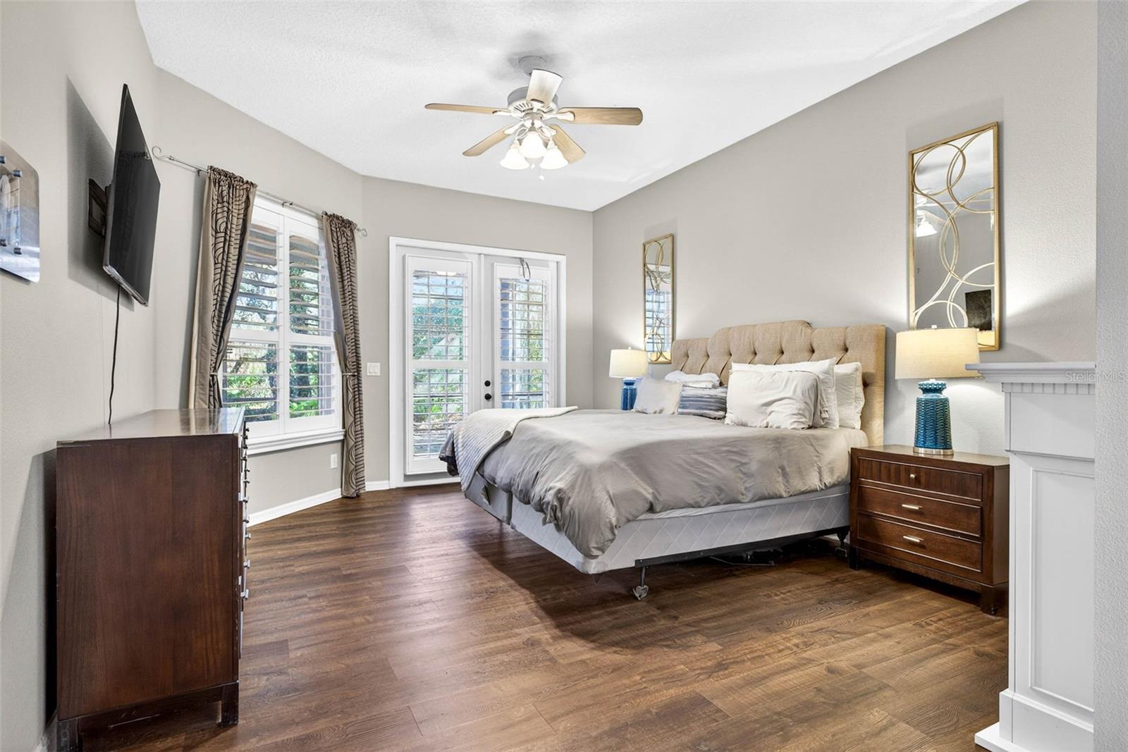 Primary bedroom with french doors that open on to the lanai and views of the maturely landscaped backyard oasis.