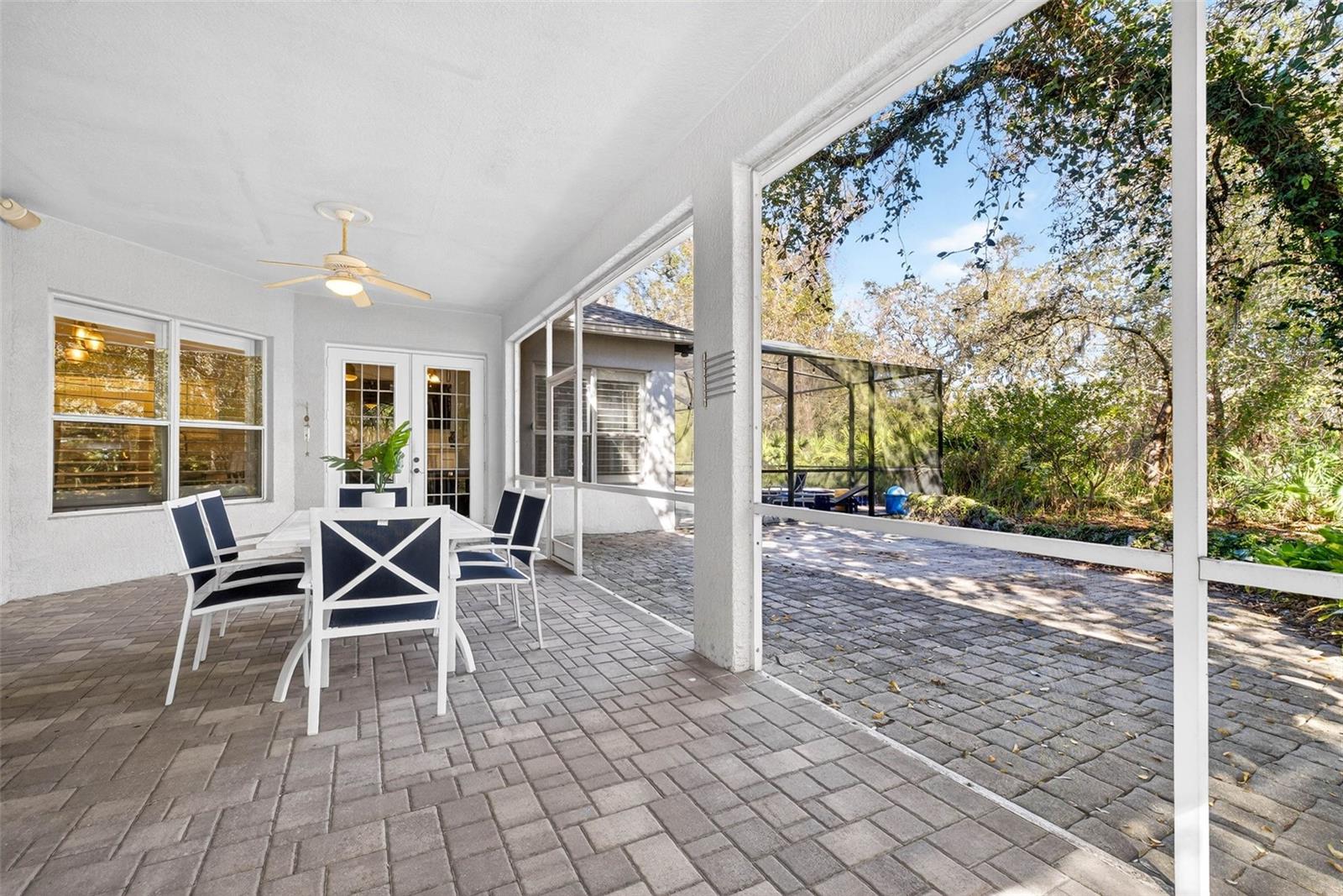 Screened lanai overlooking pavered area and mature landscaping. Pool and spa are in separate screened area.