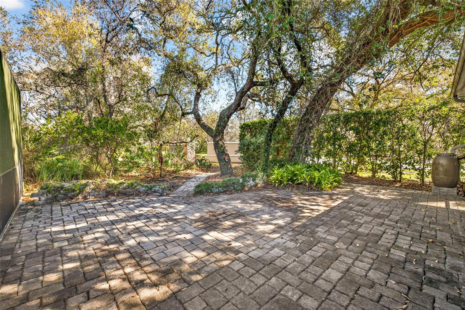 Extended, pavered outdoor area for enjoying the beautiful, mature, landscaping.Cistern on right hand side drains water from house to side yard.