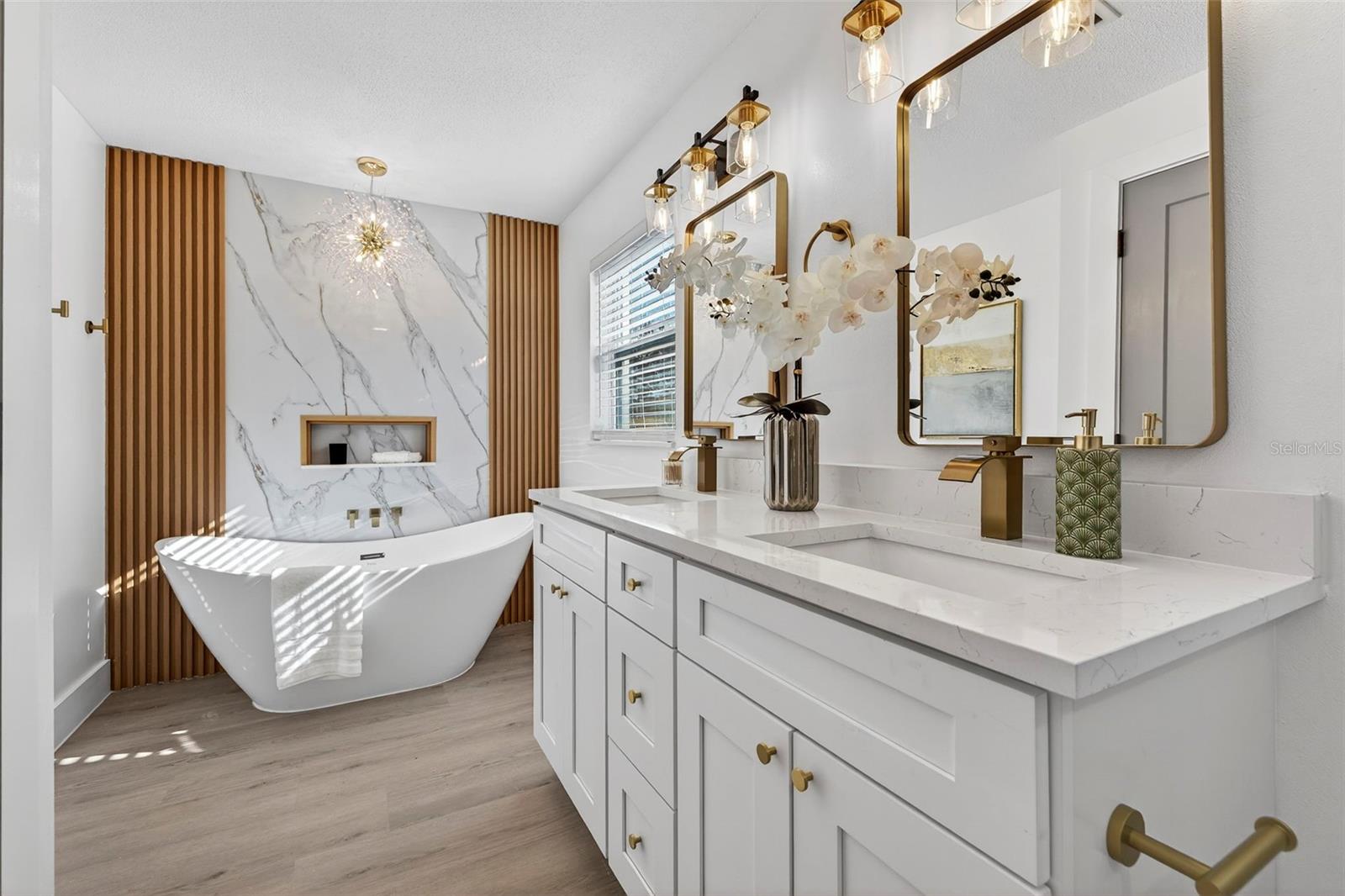 Spa-style bath with DOUBLE VANITY WITH QUARTZ COUNTERS and gold fixtures.