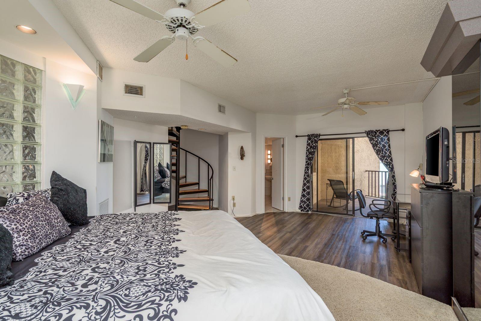 master bedroom, spiral staircase, master bathroom door, sliding glass door to patio