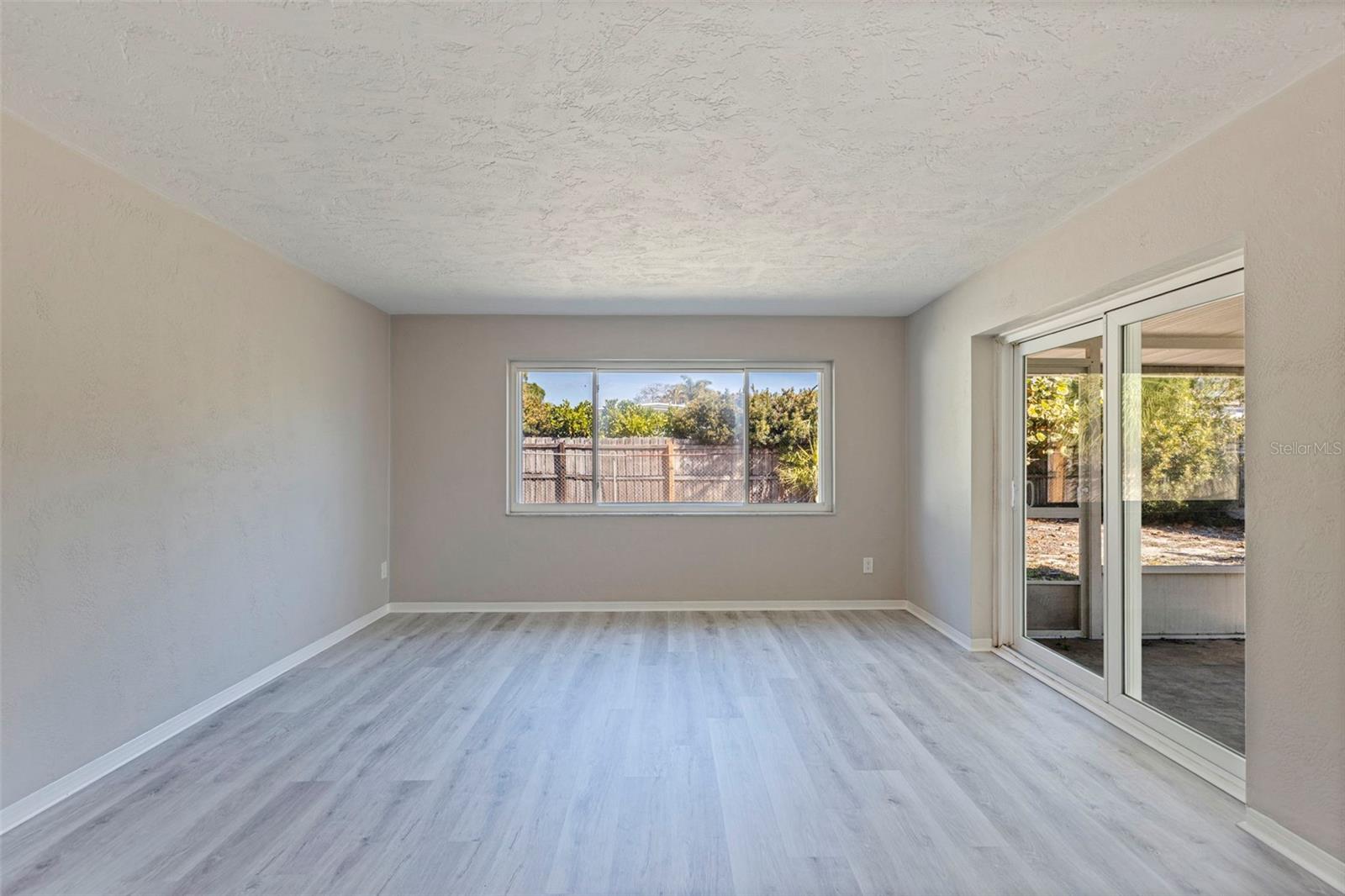Light-filled Florida room offering flexible space for a second living area, office, or hobby room. Large rear window and sliding glass doors provide natural light and views of the fenced backyard. Direct access to the screened porch extends the living area and creates an easy indoor-outdoor connection. Updated vinyl plank flooring continues seamlessly from the main living areas for a cohesive finish.