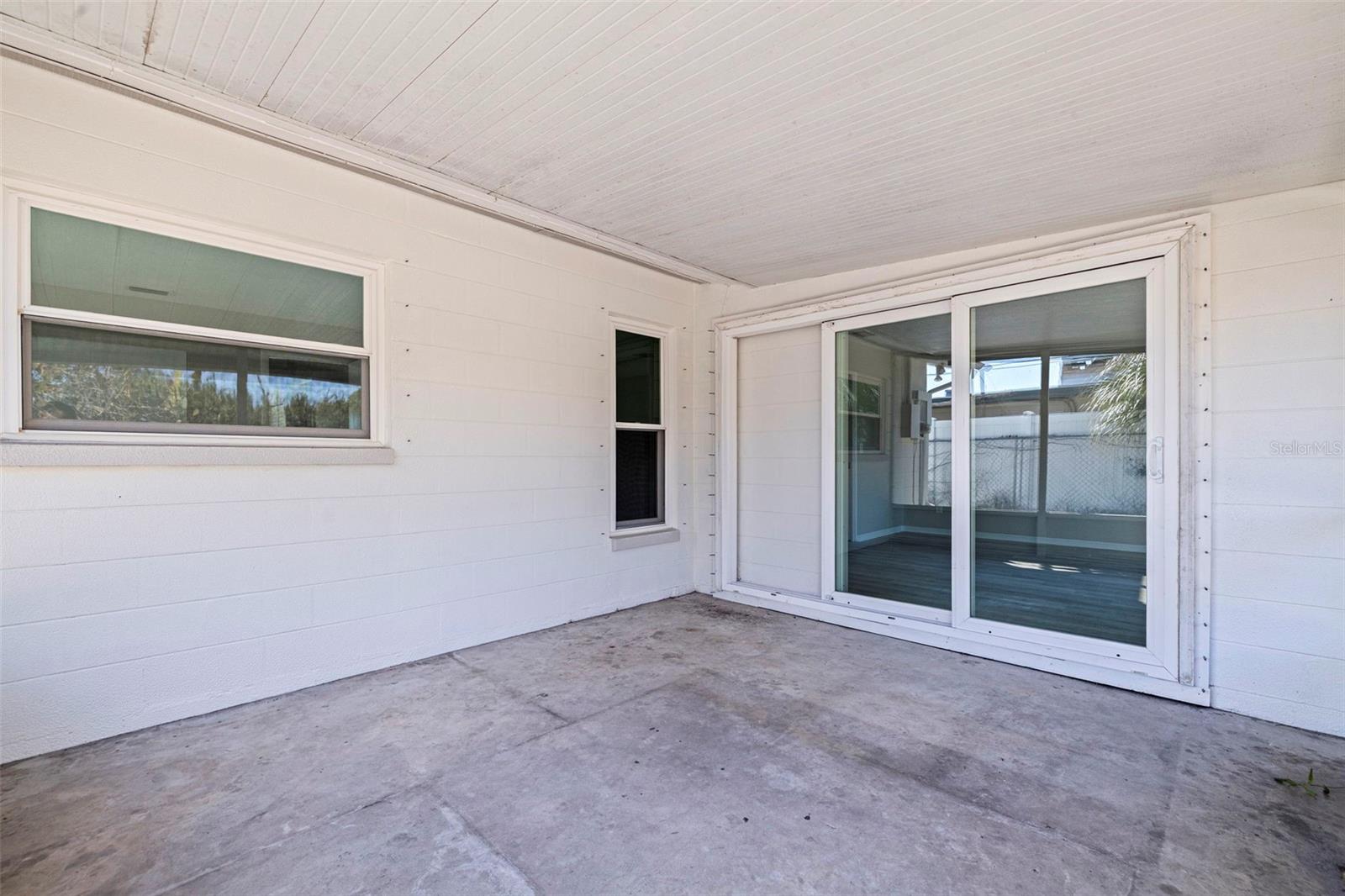 Covered and screened porch offering a protected outdoor living space ideal for seating or casual dining. Concrete flooring provides durability and low maintenance, while sliding glass doors connect directly to the Florida room for convenient indoor-outdoor flow. The screened enclosure allows for fresh air enjoyment with added privacy from the fenced backyard.