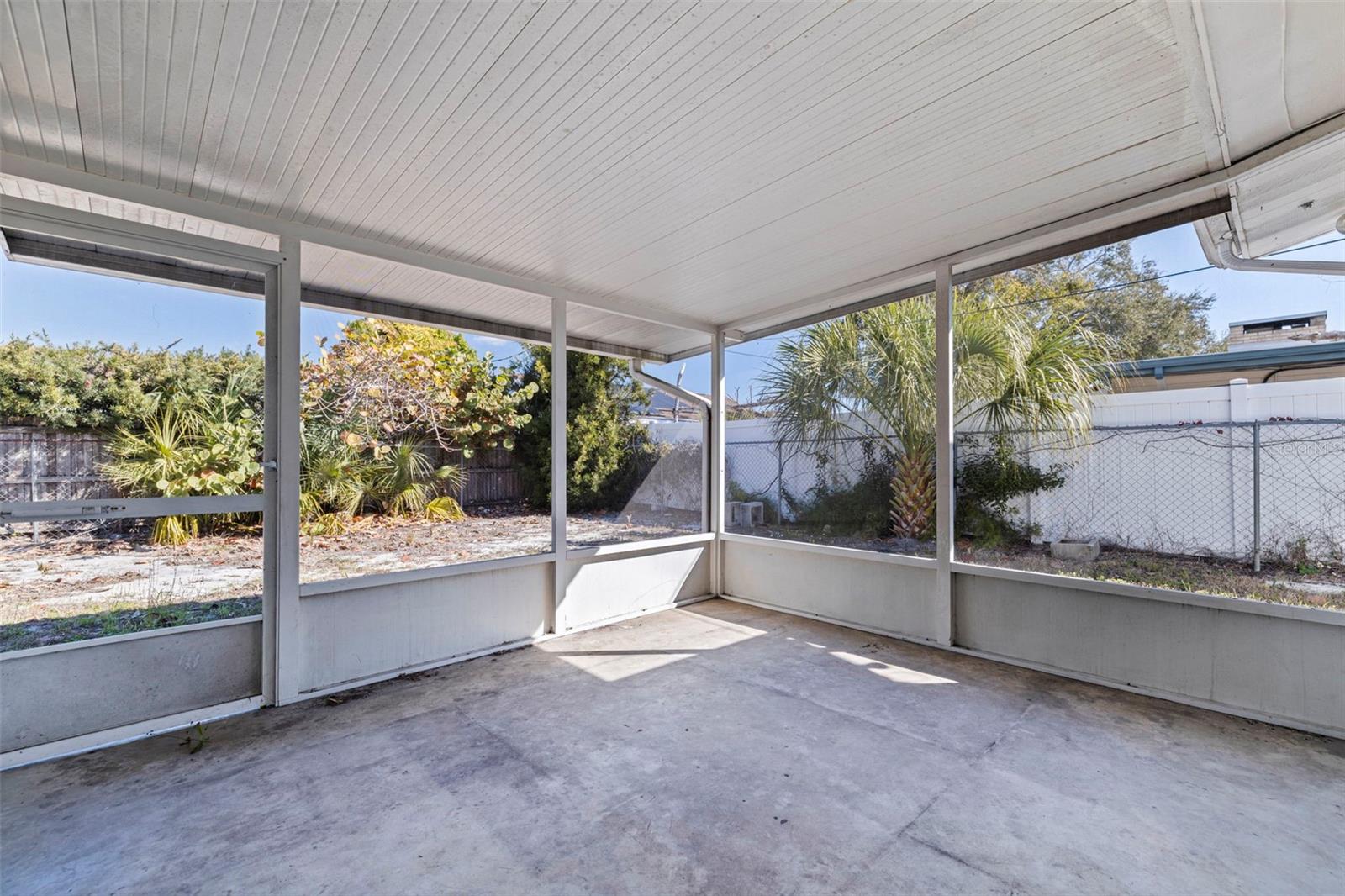 Spacious screened porch overlooking the private backyard, offering an airy extension of the living space. The covered design provides shade and year-round usability, while wide screened panels invite natural light and cross-breezes. Concrete flooring ensures durability and easy upkeep, creating a versatile setting for outdoor seating, morning coffee, or relaxed evening gatherings.