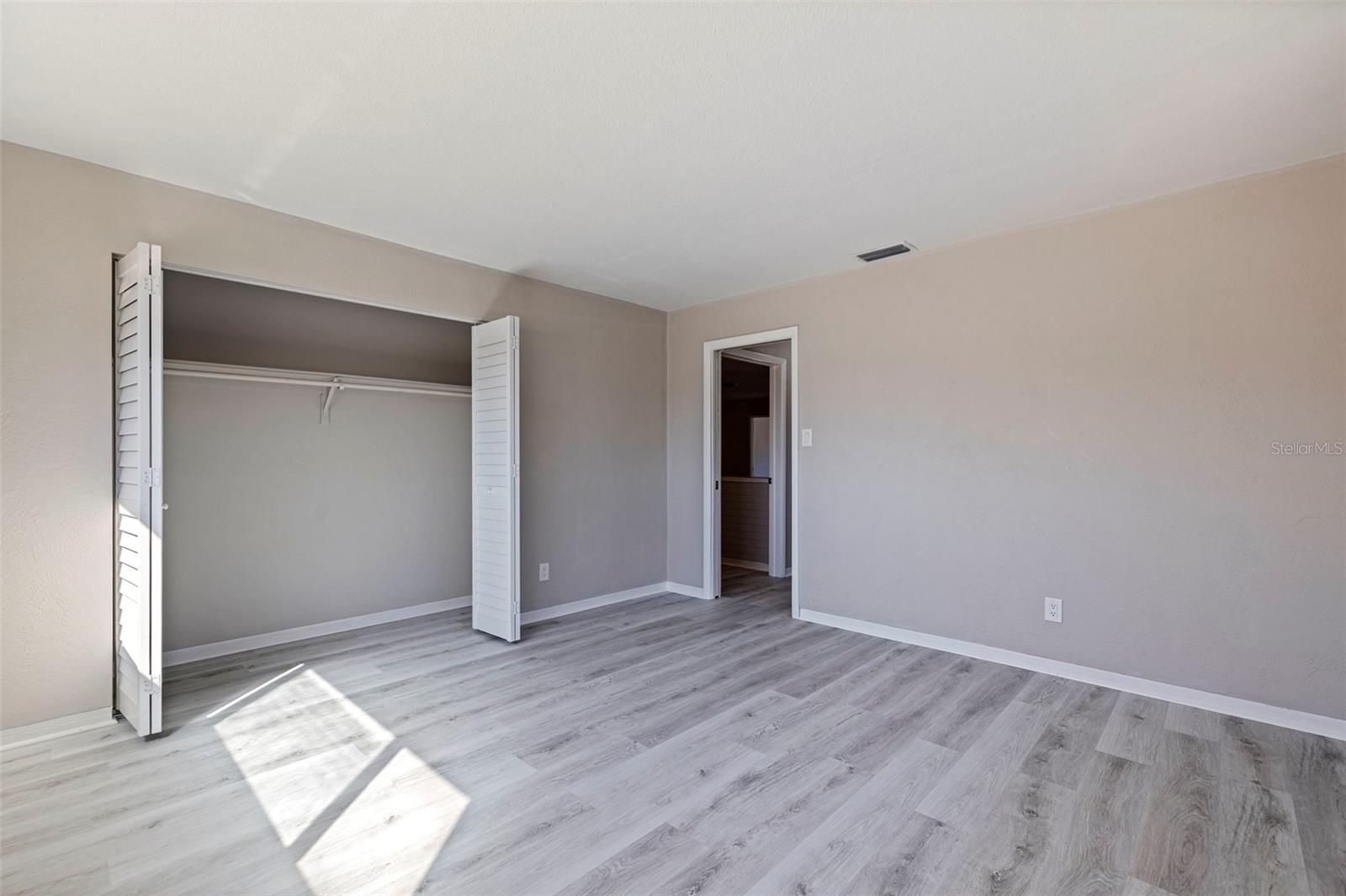 2nd bedroomBedroom 2 offering a spacious layout with updated vinyl plank flooring and neutral finishes. A wide closet with bifold doors provides ample storage, while the clean lines and natural light create a comfortable setting for guests, family, or a dedicated workspace.