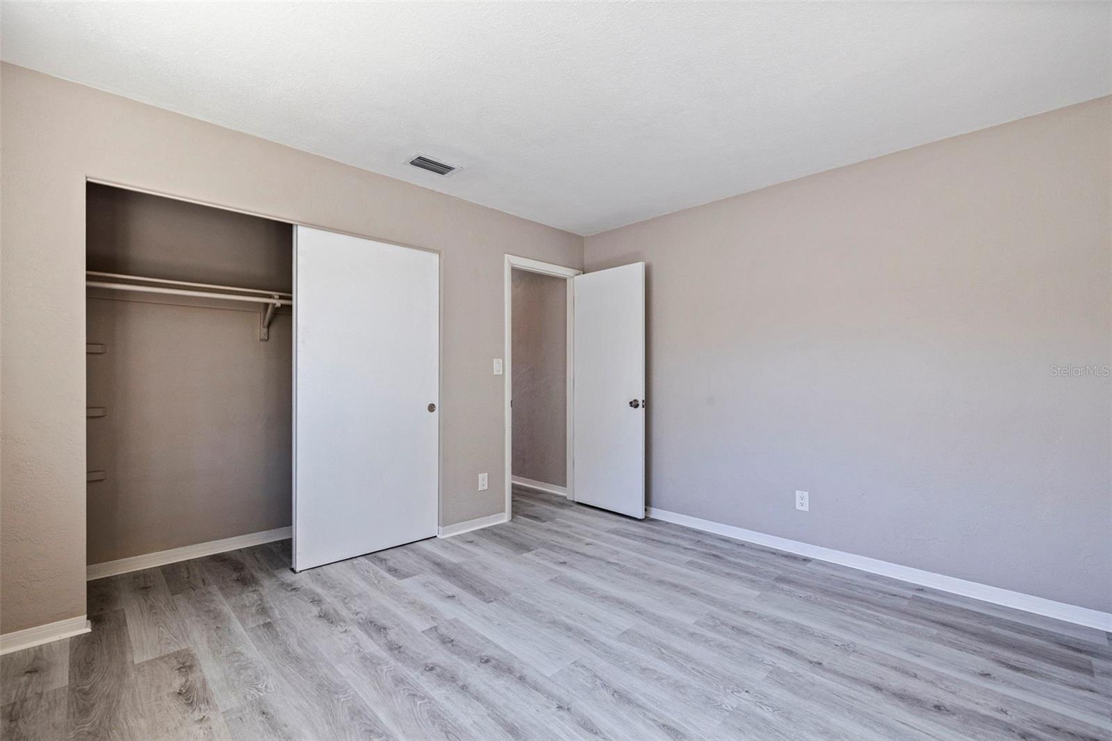 Bedroom 3 with updated vinyl plank flooring and a neutral color palette for a clean, move-in-ready feel. A built-in closet with sliding doors provides convenient storage, while the spacious layout offers flexibility for guests, family members, or a home office setup.