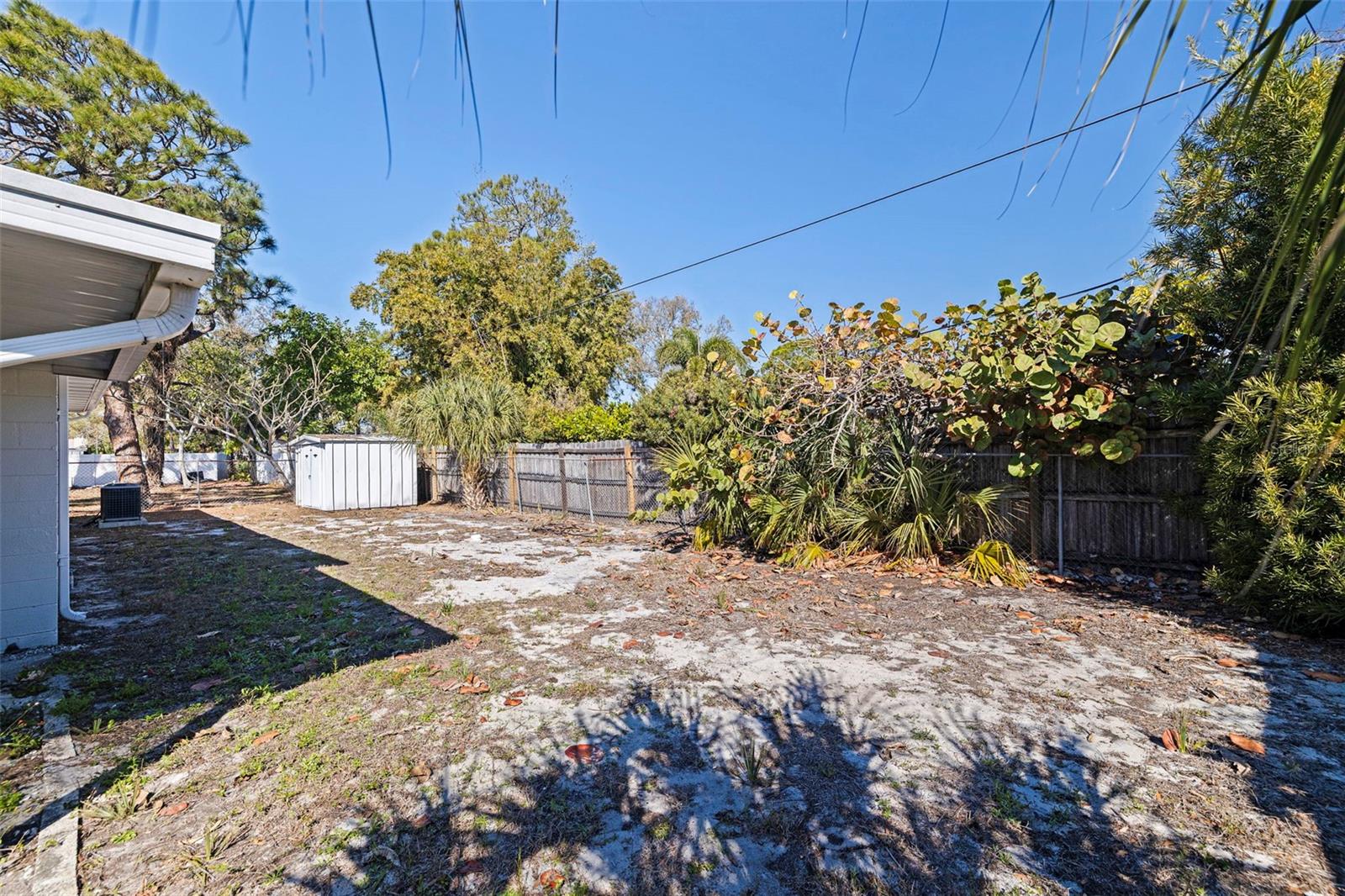 The expansive yard provides plenty of room for pets, gardening, or future enhancements, while mature trees and established greenery create a natural backdrop. A detached storage shed adds convenient space for tools and equipment.