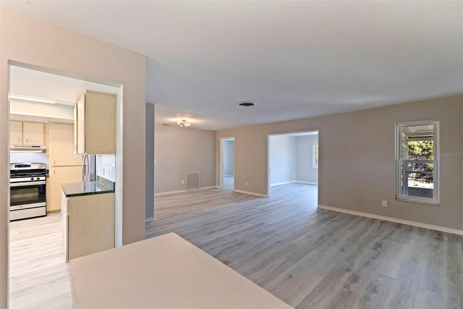 Bright, open living and dining area featuring updated vinyl plank flooring and neutral interior finishes throughout. The layout connects seamlessly to the kitchen, creating an easy flow.