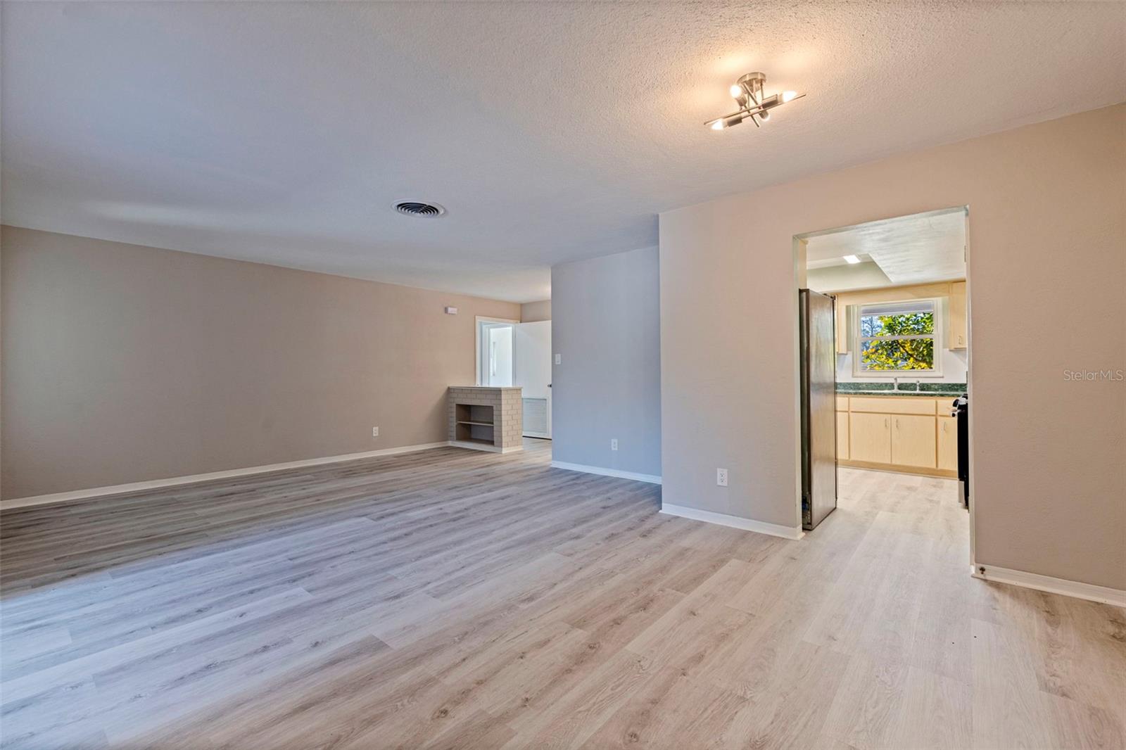 Spacious combined living and dining area featuring updated vinyl plank flooring and neutral interior finishes. The open layout provides flexibility for furniture placement and everyday living, with a clear connection to the kitchen for convenient flow. Modern overhead lighting enhances brightness and accessibility throughout the main living space.