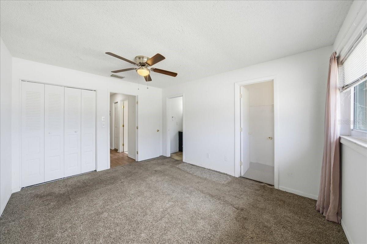 Primary bedroom with en-suite bathroom, two closets including a walk-in, large window and plush carpet flooring for comfort.