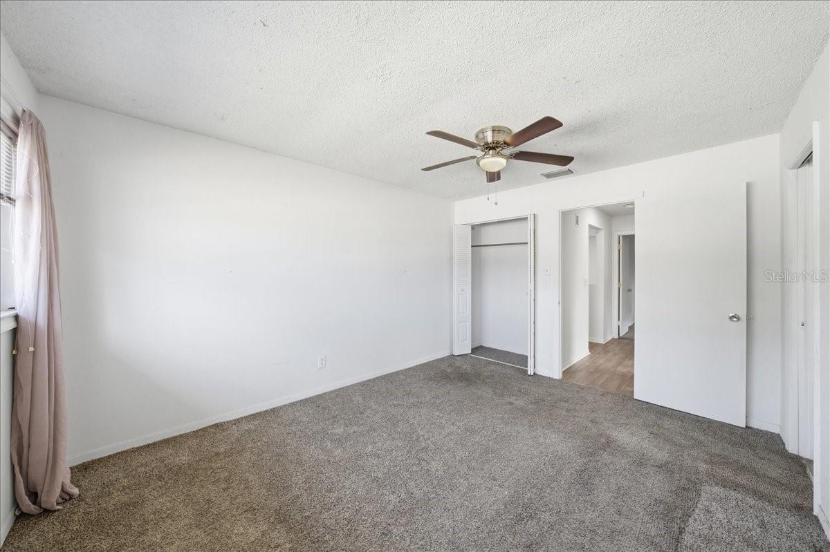 Primary bedroom with en-suite bathroom, two closets including a walk-in, large window and plush carpet flooring for comfort.