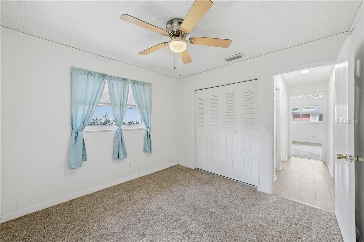 Second bedroom with wainscoting, two windows, wall closet and comfort carpeting