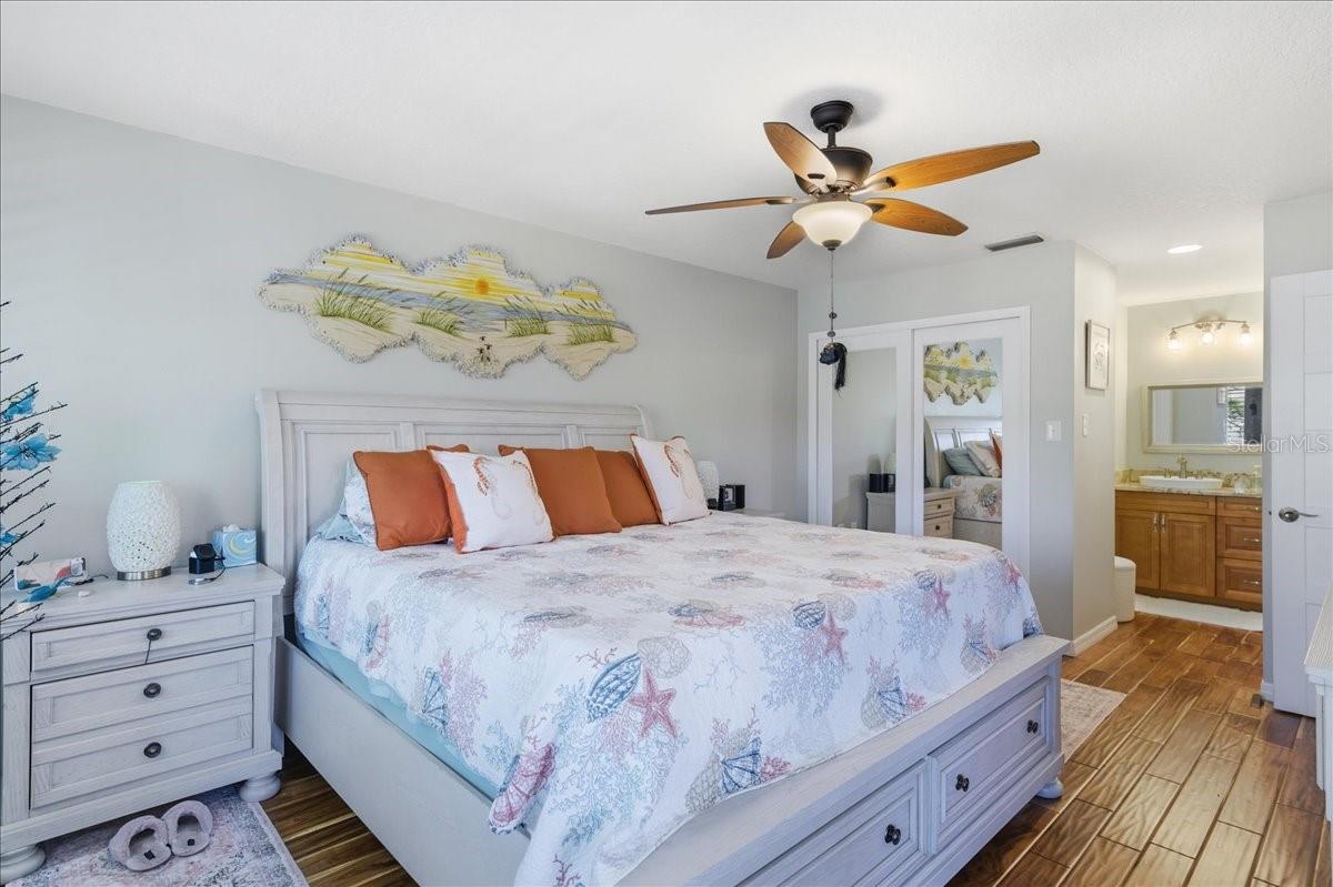The primary bedroom enjoys beautiful water views, private sliding glass doors to the balcony, two closets with California Closet organizers, beautiful wood-look tile flooring, tastefully updated en-suite bathroom with a vanity room separate from the shower.