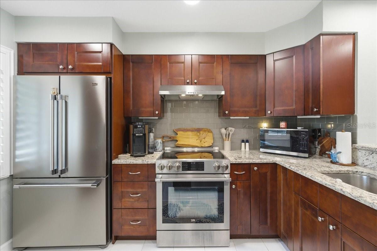 Stunning updated kitchen is well-equipped with stainless-steel appliances including a convection oven, rich cherry wood cabinets with soft closing cabinets and drawers, granite countertops, and beautiful, easy maintenance tile floors that flow into the main living areas.