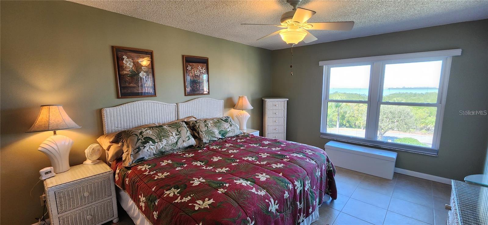 The large primary bedroom has the gulf view, has a collection of white wicker furniture and is...