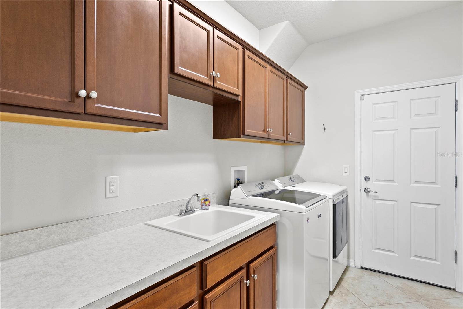 Laundry room features a utility sink with cabinets for additional storage