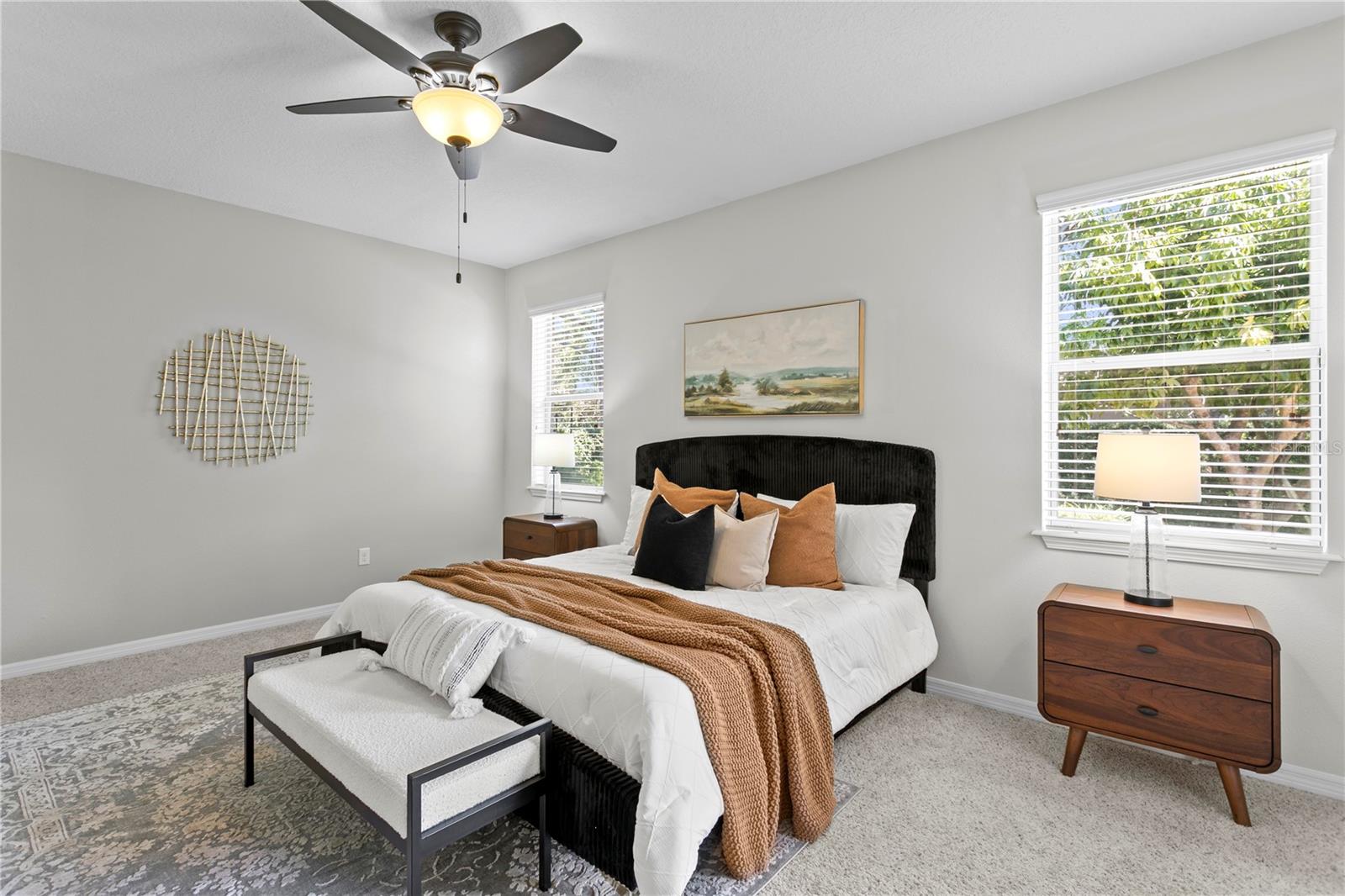 Large primary bedroom with ceiling fan and carpet flooring