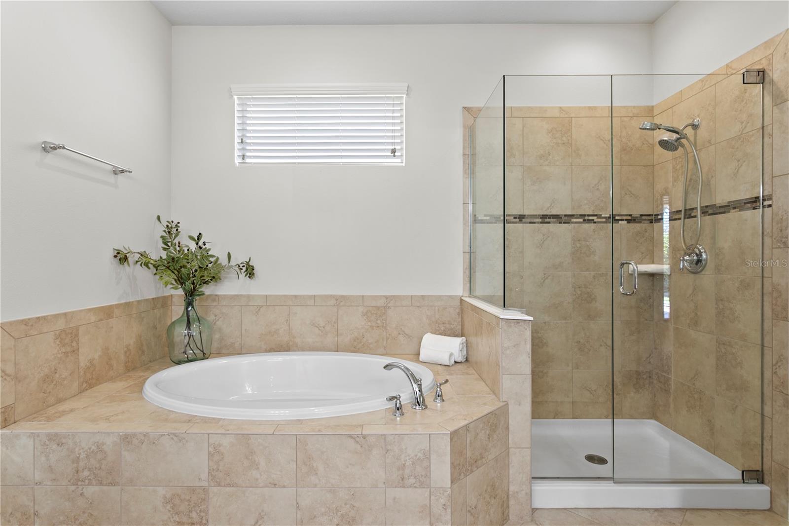 Primary bath features a garden tub with separate tile shower