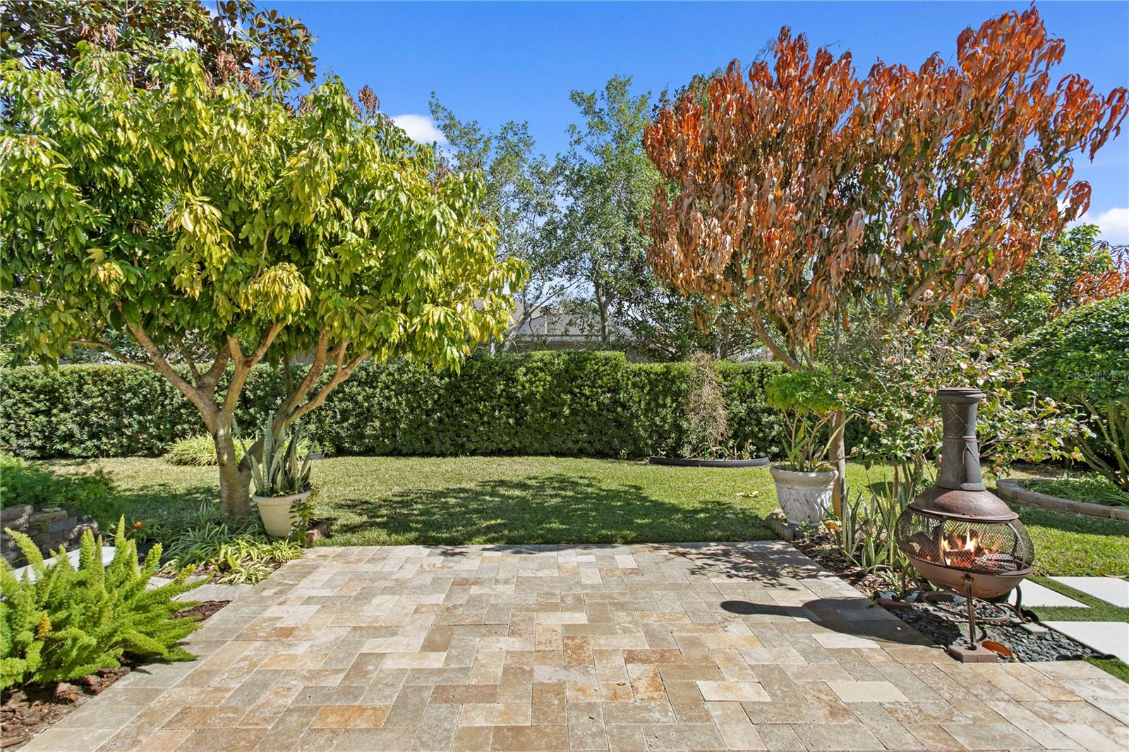 Large paver patio surrounded by meticulously maintained landscaping