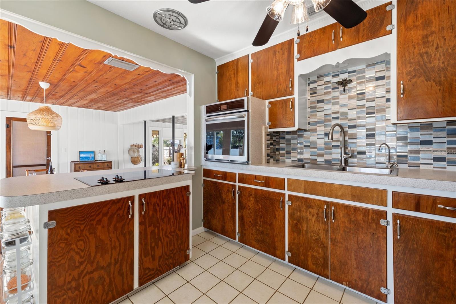 Kitchen with wood cabinetry, tile backsplash, and solid surface counters.