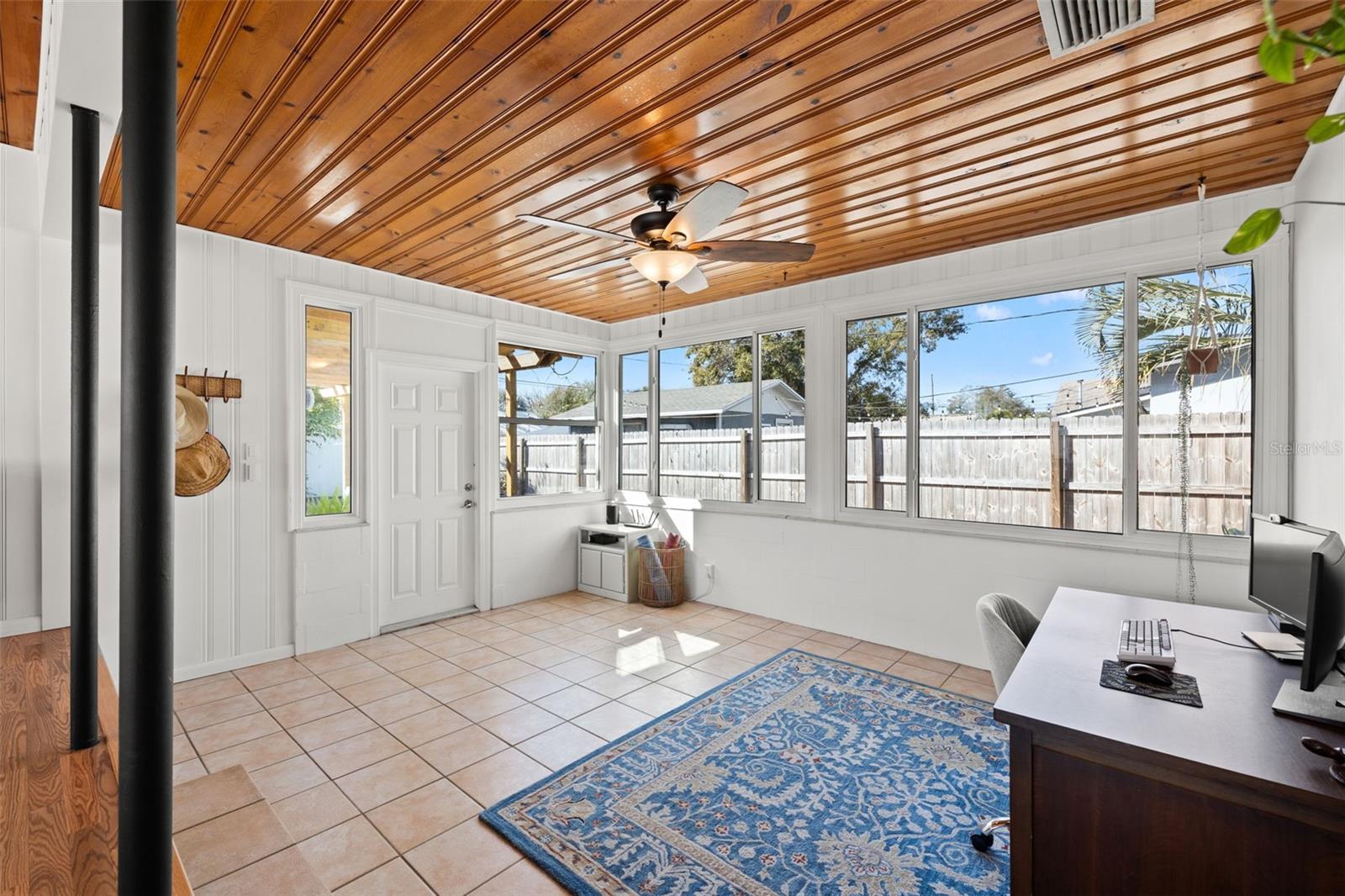 Rear flex/bonus room with wood plank ceiling, tile flooring, and multiple windows.