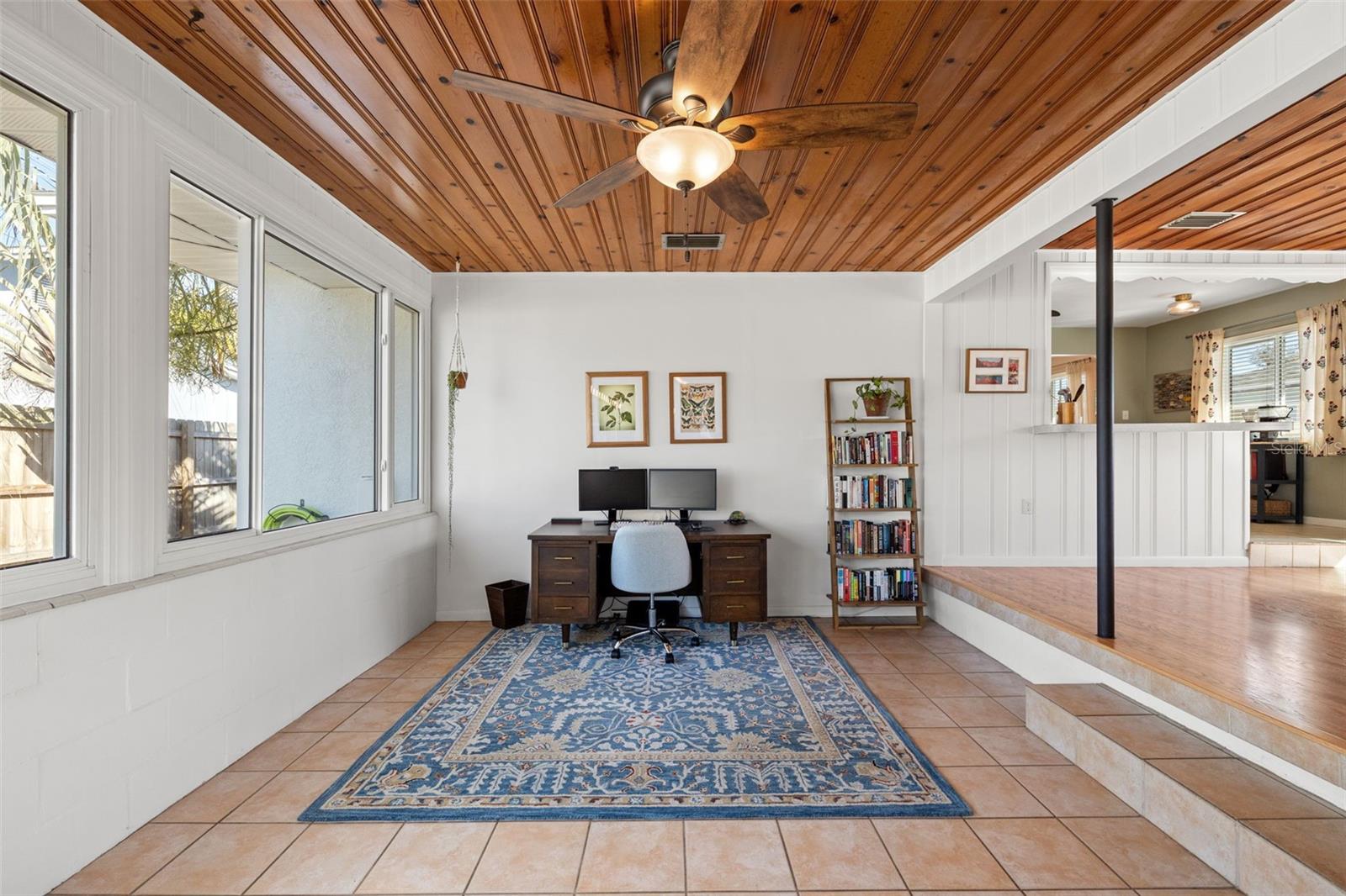 Versatile bonus space featuring a warm wood plank ceiling, tile flooring, and abundant natural light. Ideal for a home office, creative studio, or reading lounge, with convenient access to the main living areas.