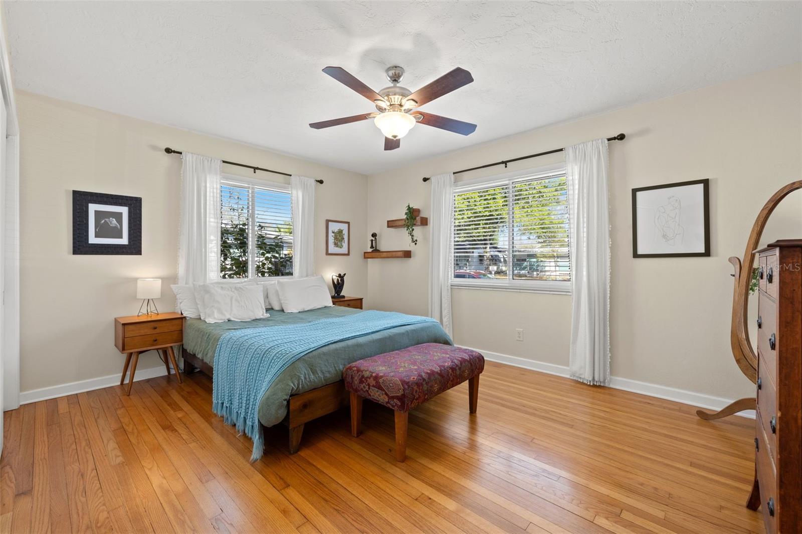 Primary bedroom with hardwood floors and window views.