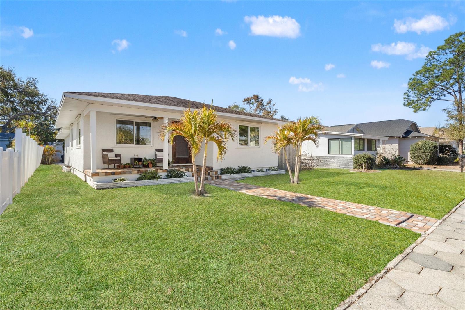Brick-lined street setting with covered rocking chair front porch and paver walkway.