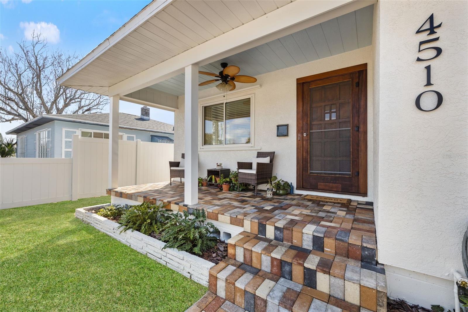 Relax on the covered front porch with stylish paver flooring, ceiling fan, and space for seating—ideal for enjoying morning coffee or evening breezes.