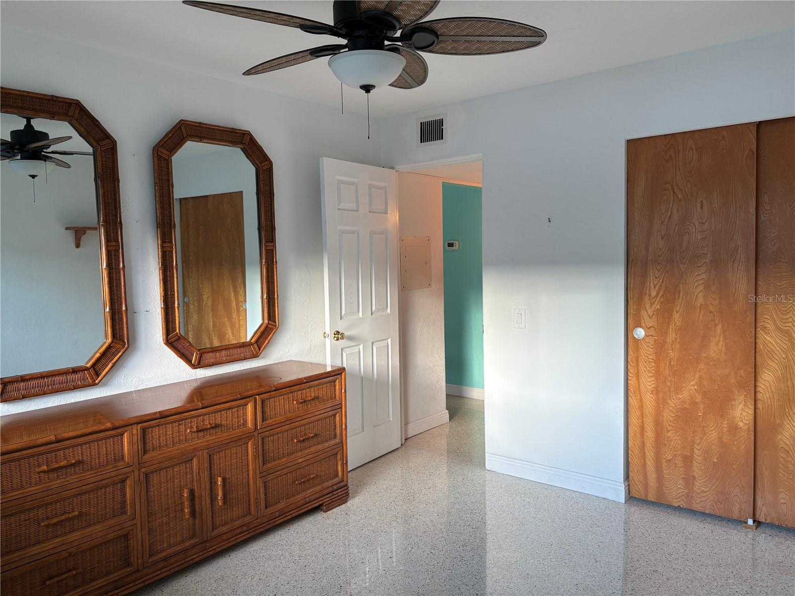 2nd bedroom with terrazzo flooring and decorative ceiling fan.