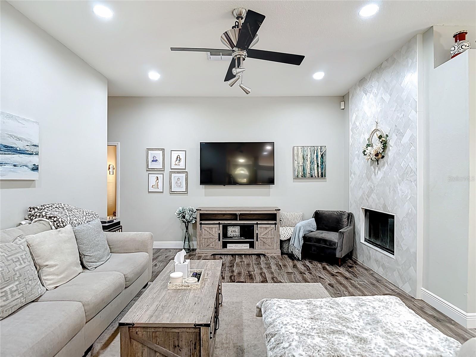 The family room features a charming wood-burning fireplace updated with white marble tile in a beautiful herringbone pattern — creating a warm and inviting focal point.