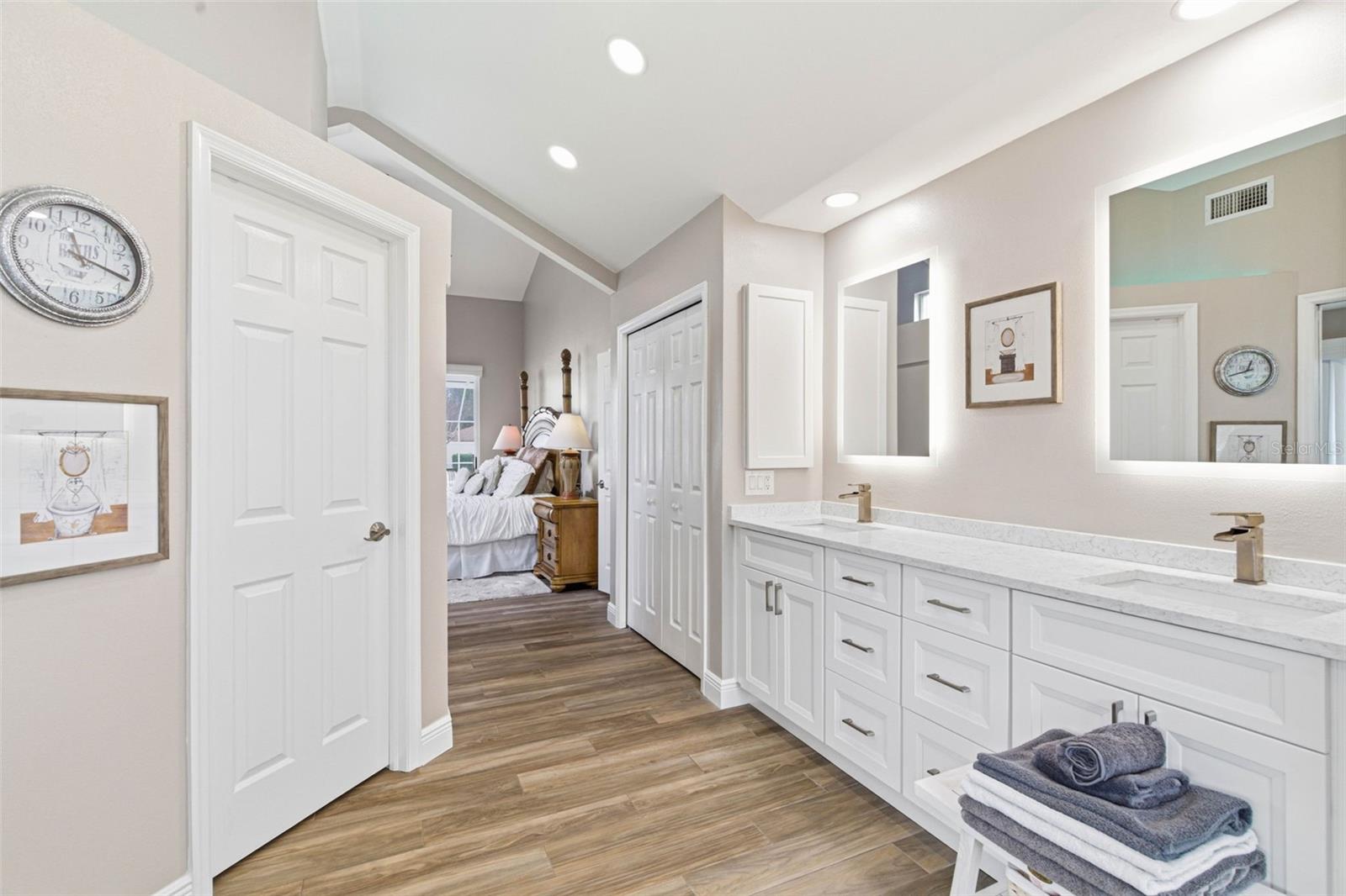 Beautifully finished vanity area with abundant cabinetry, dual sinks, illuminated anti-fog mirrors and modern recessed lighting.