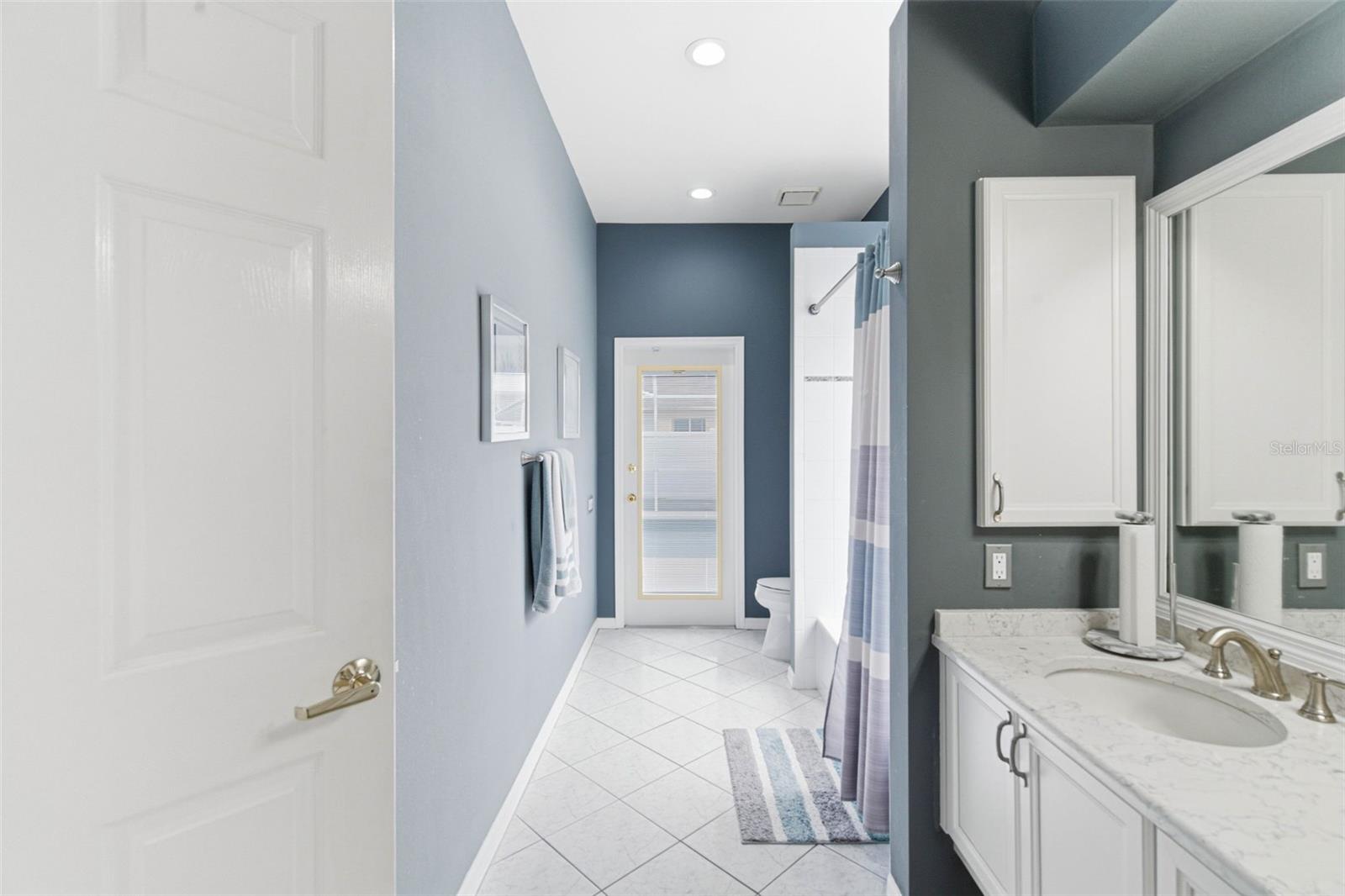 Modern full guest bathroom with an updated shower and bathtub plus a dedicated door leading directly to the pool area.