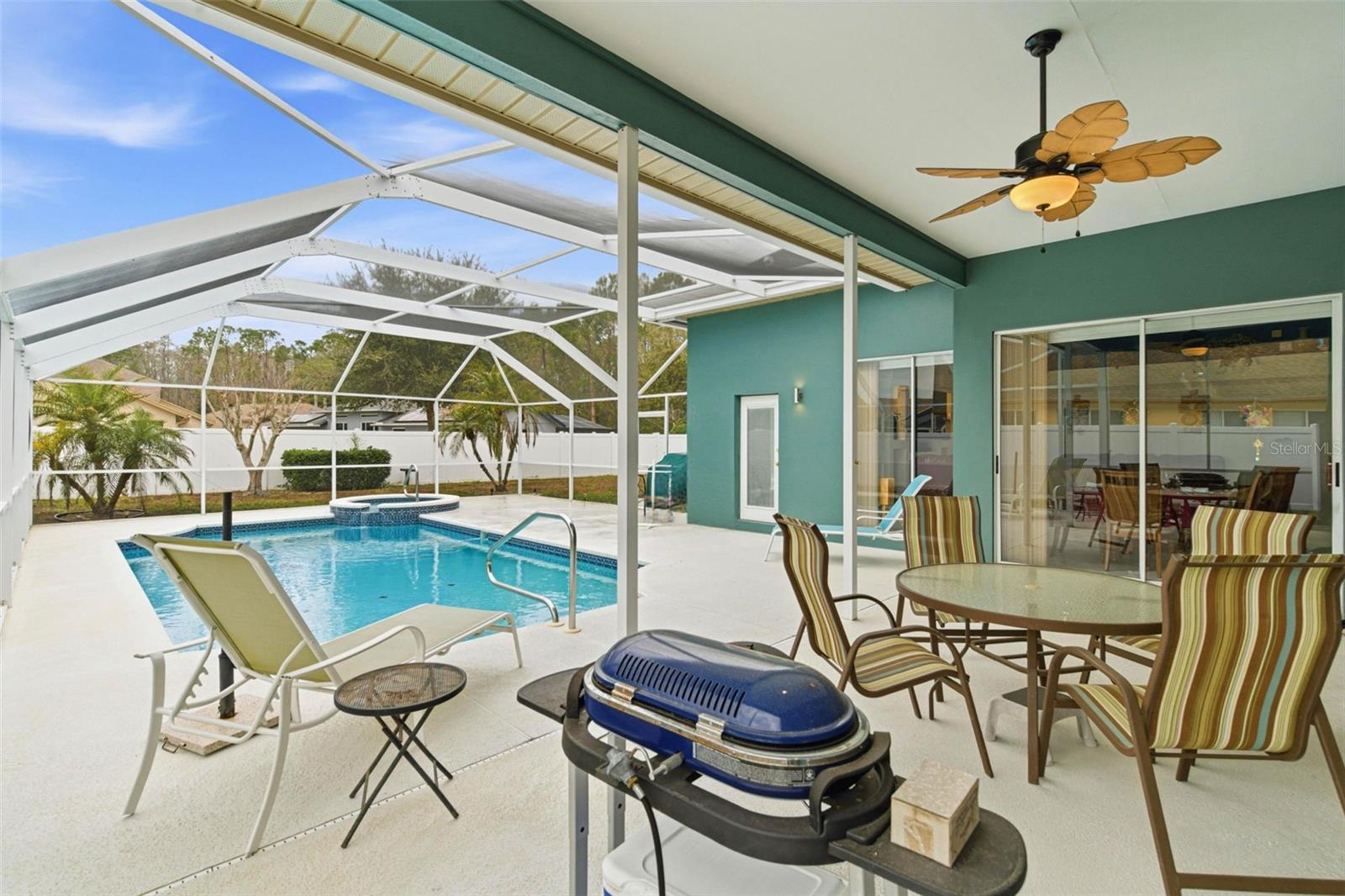 Relax under the covered deck overlooking the screened pool and tropical palm trees backdrop