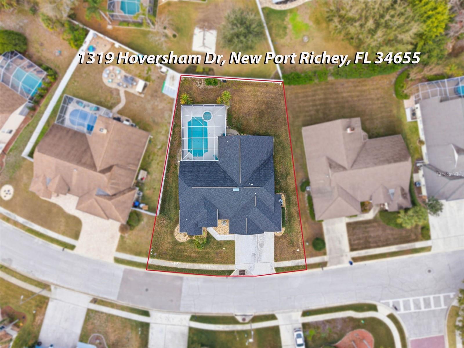 Aerial shot capturing the home, lanai-enclosed pool, tropical landscape for a full view of the property.
