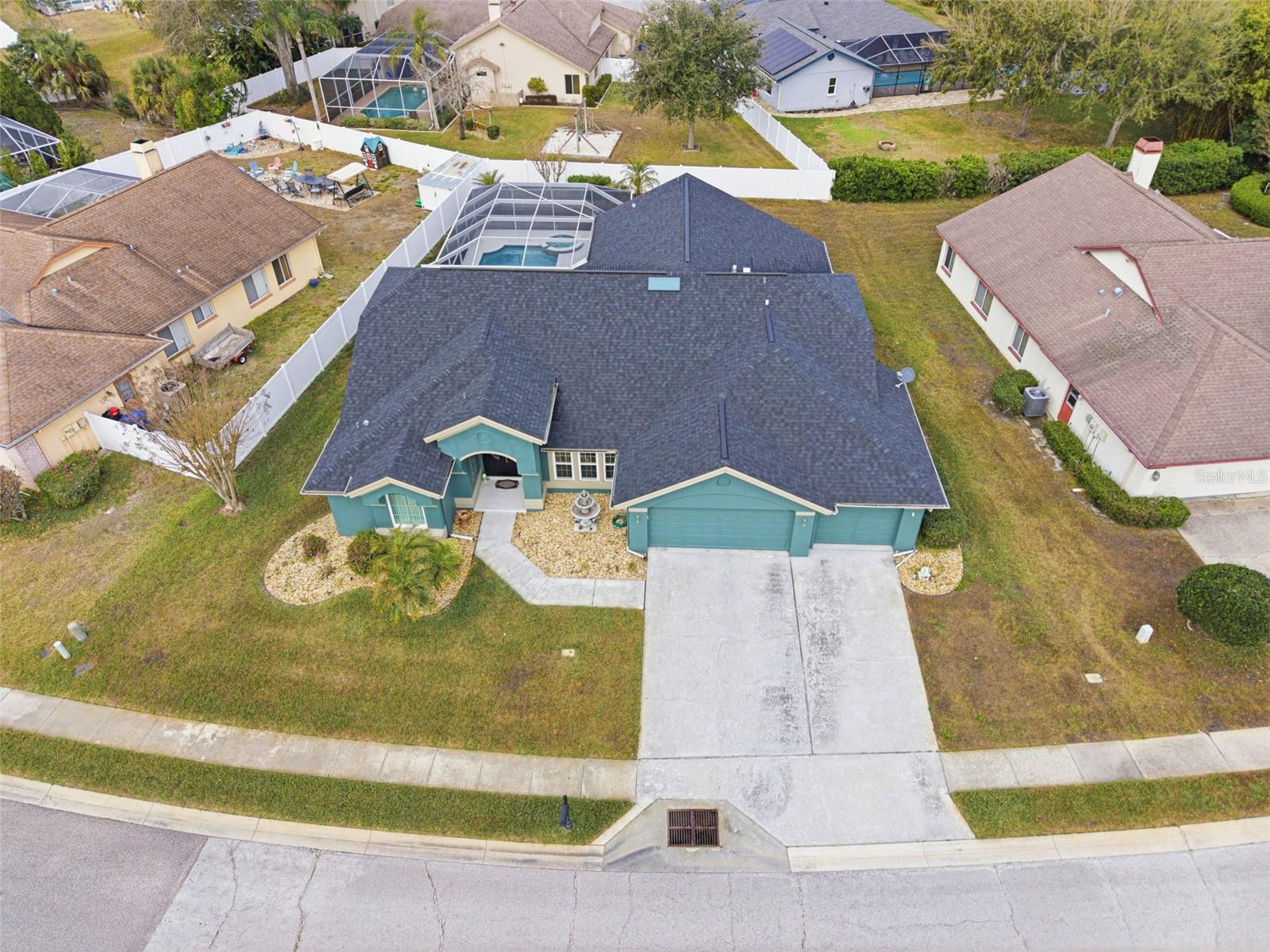 Overhead view of the residence framed by manicured palm landscaping in the front yard and backyard