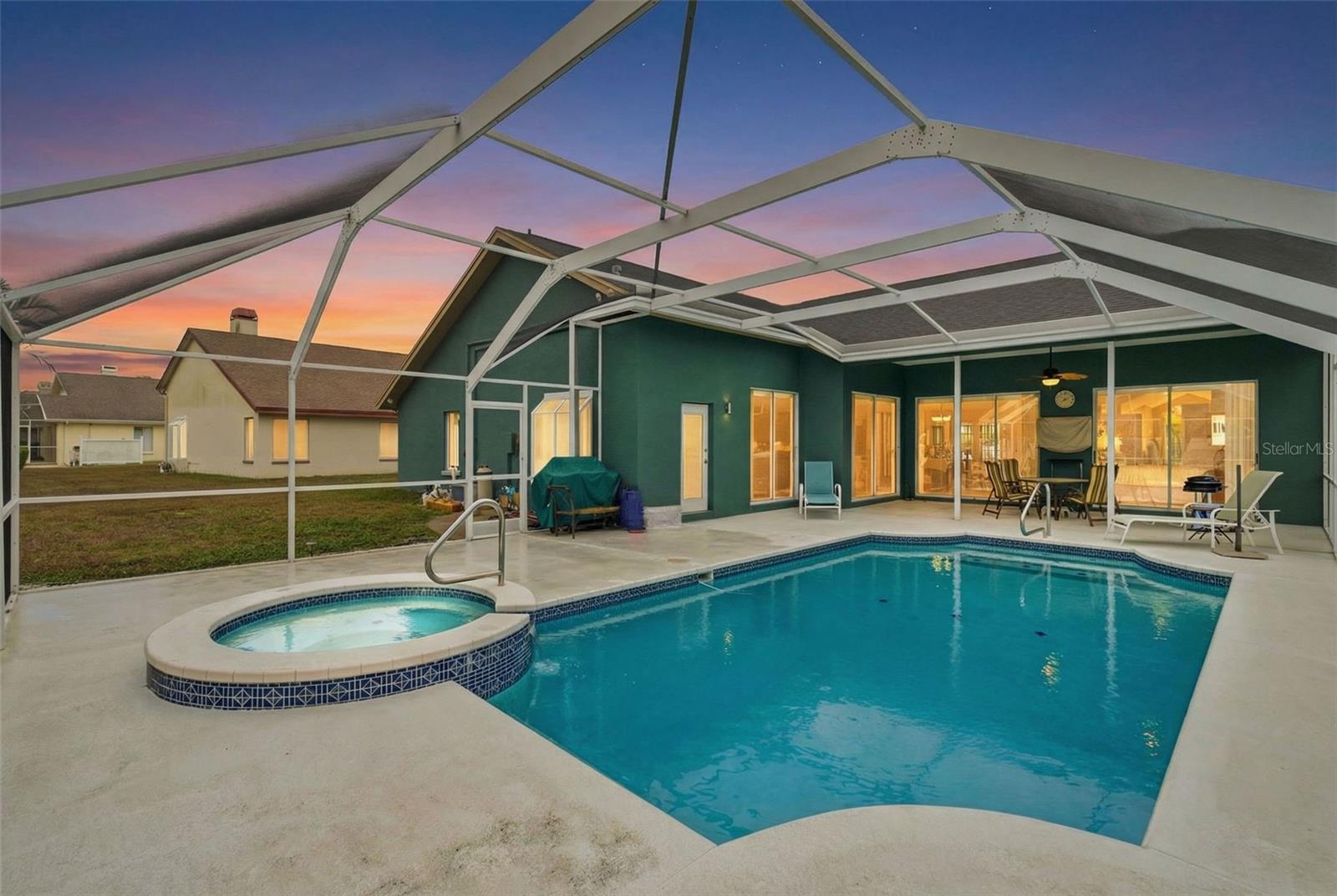 Evening virtual-twilight scene showcasing the resurfaced pool and spa inside the screened enclosure