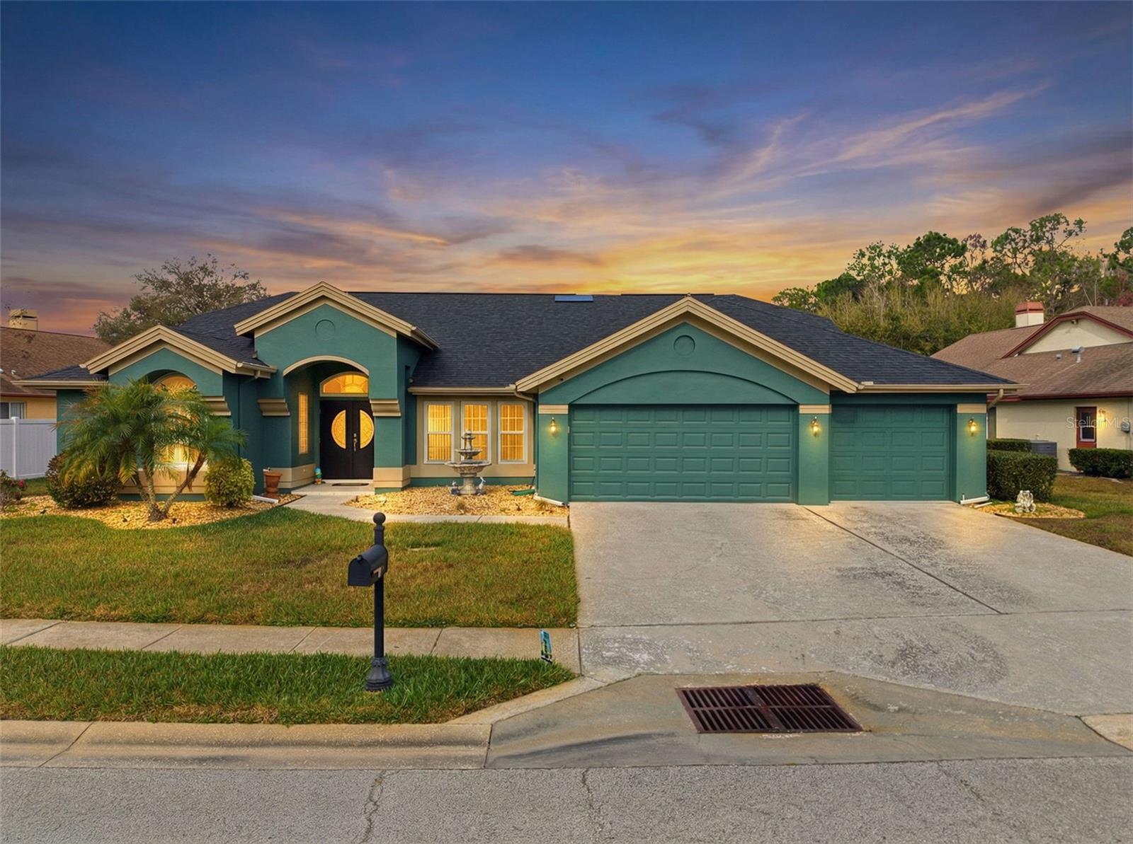 Evening virtual-twilight view highlighting the home and its well-kept palm landscaping.