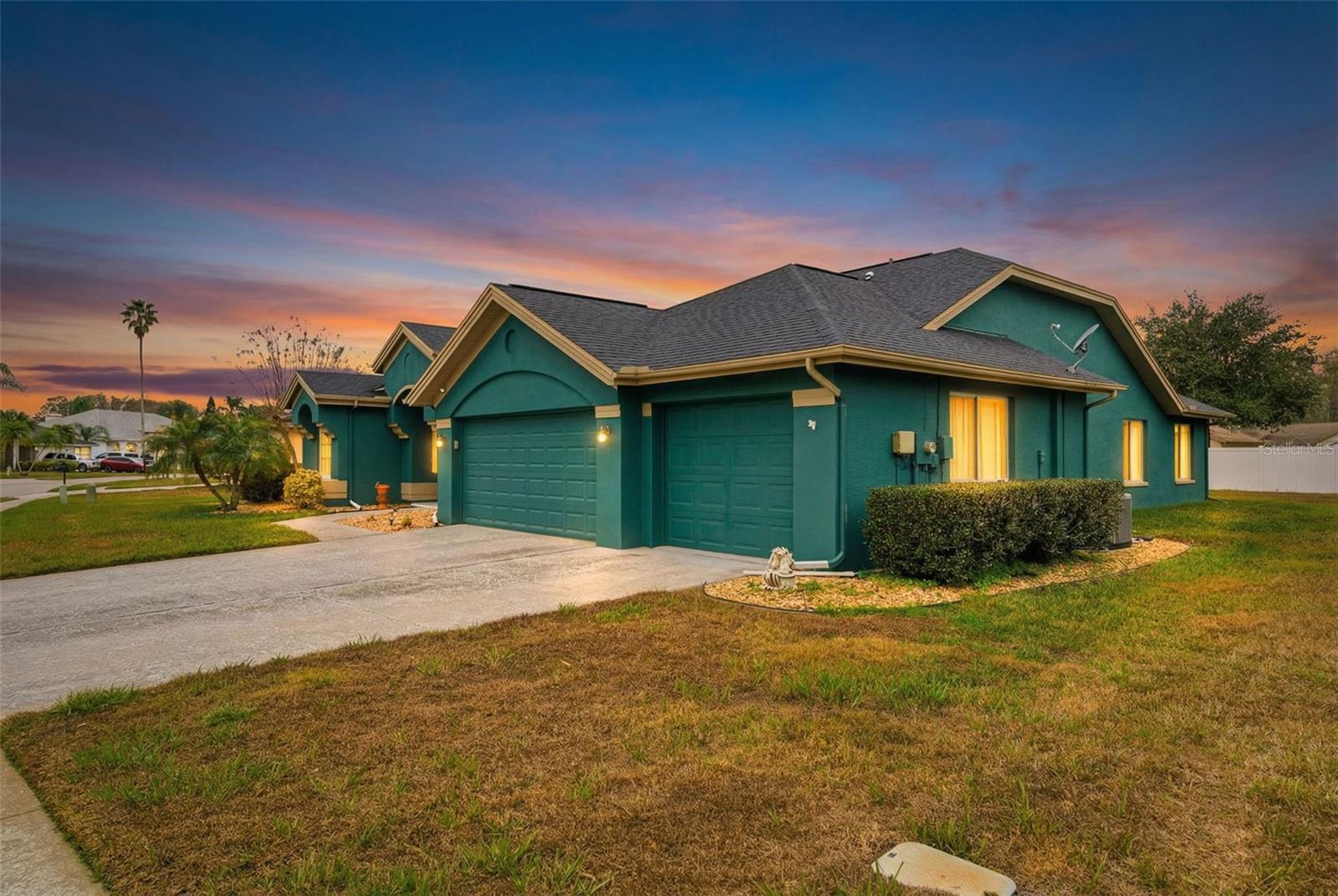 side exterior view with virtual twilight sky and manicured palm landscaping.