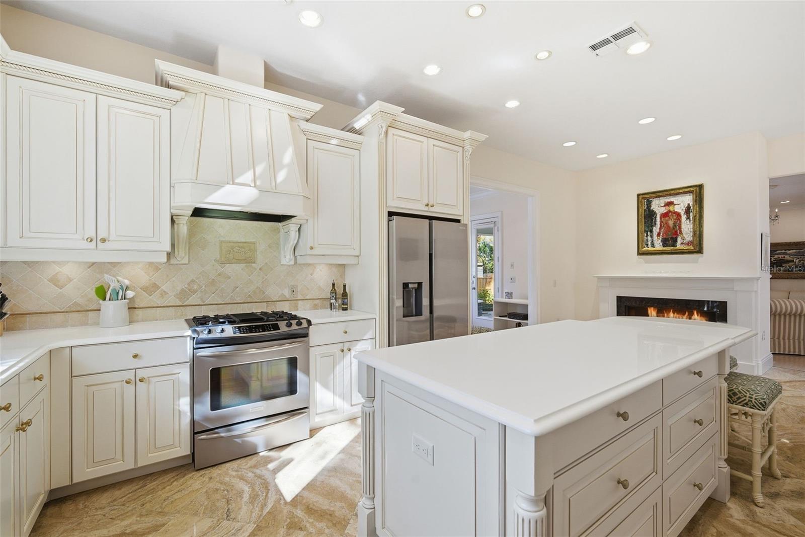 Kitchen gas range, hood, built-in convection oven and microwave, warming drawer, walk-in pantry loads of cabinet storage, and countertop space.