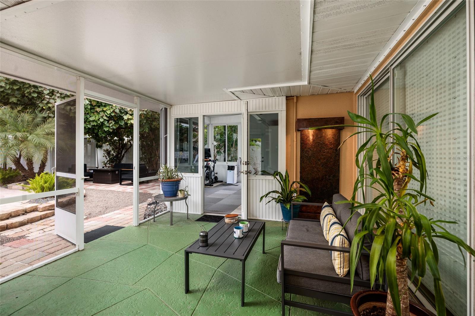 Relaxing screened outdoor patio opens to the bonus room and view of pool and fountain.