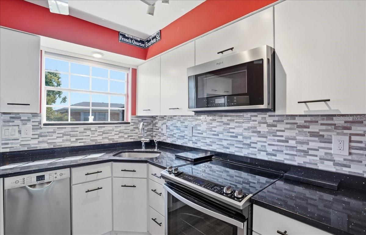 Another view of kitchen with close-up of sleek stone counters and fixtures.