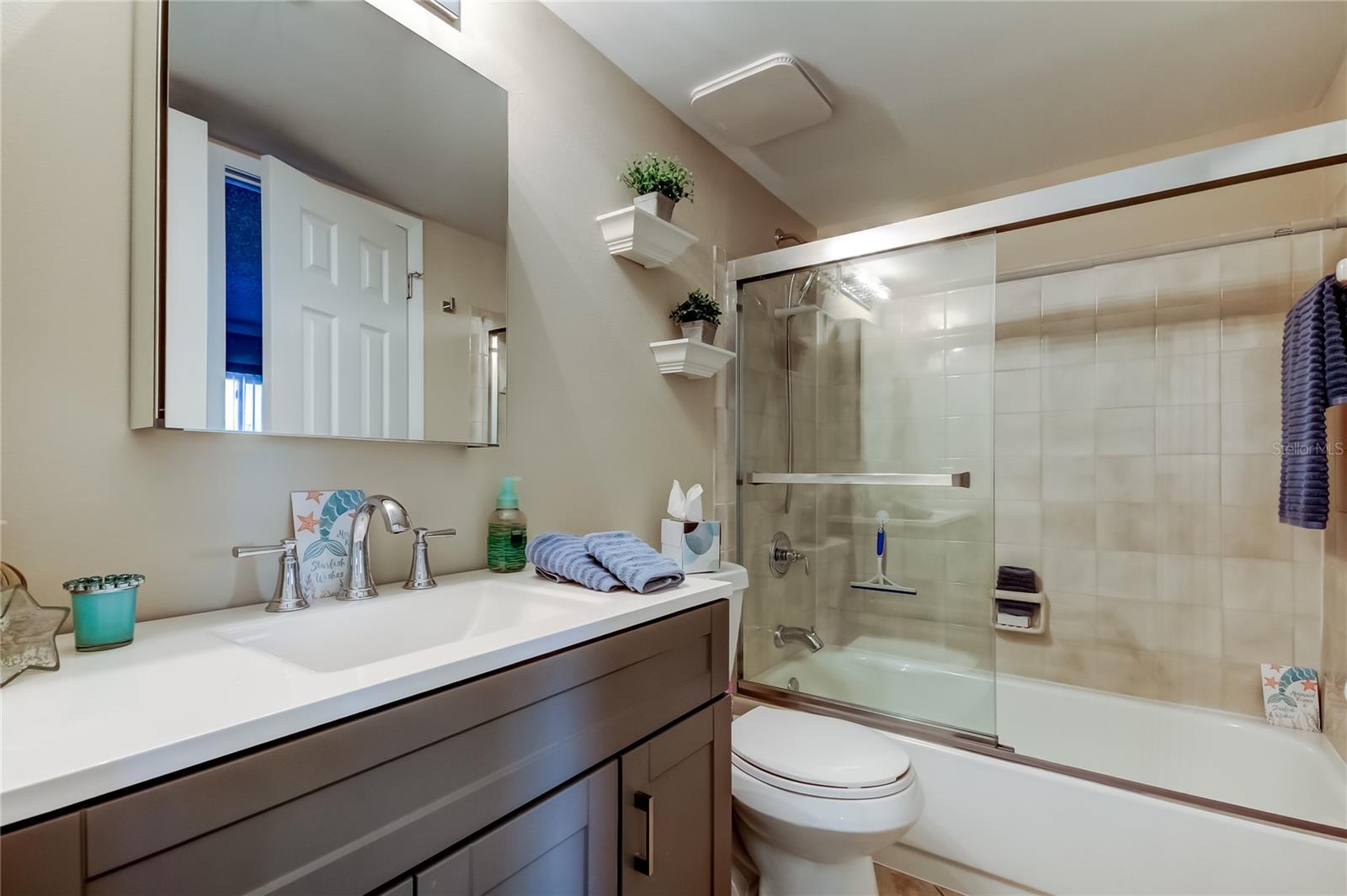 Jack and Jill bathroom that leads to Bedroom 2 and hallway has tub/shower, new slider glass door, and new vanity.