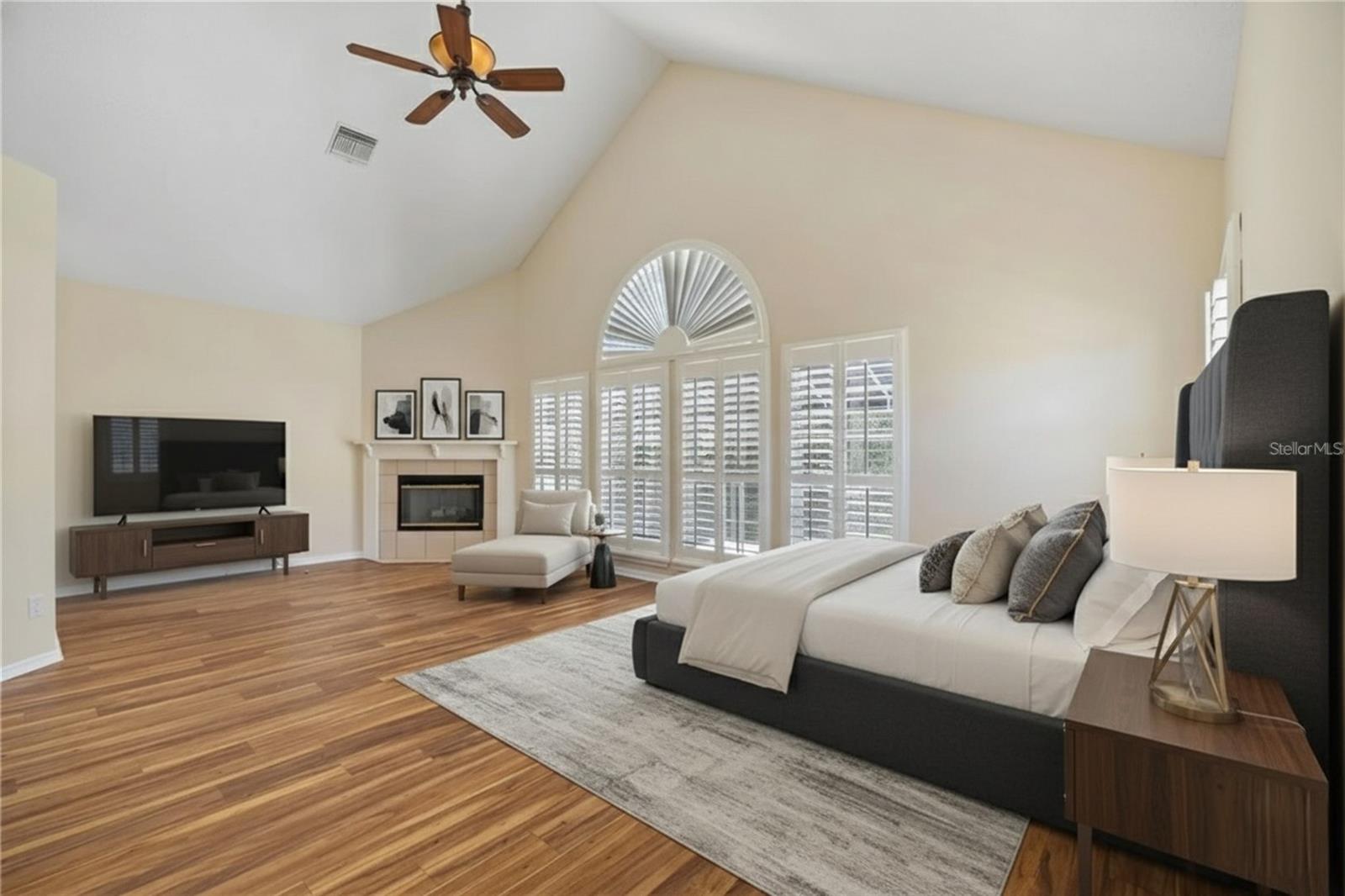 Primary Bedroom with Wood Burning Fireplace, Plantation Shutters, and Vaulted Ceilings