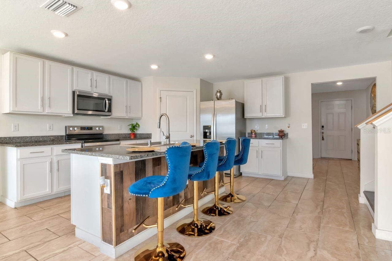 Kitchen with white cabinets, granite countertops, large island