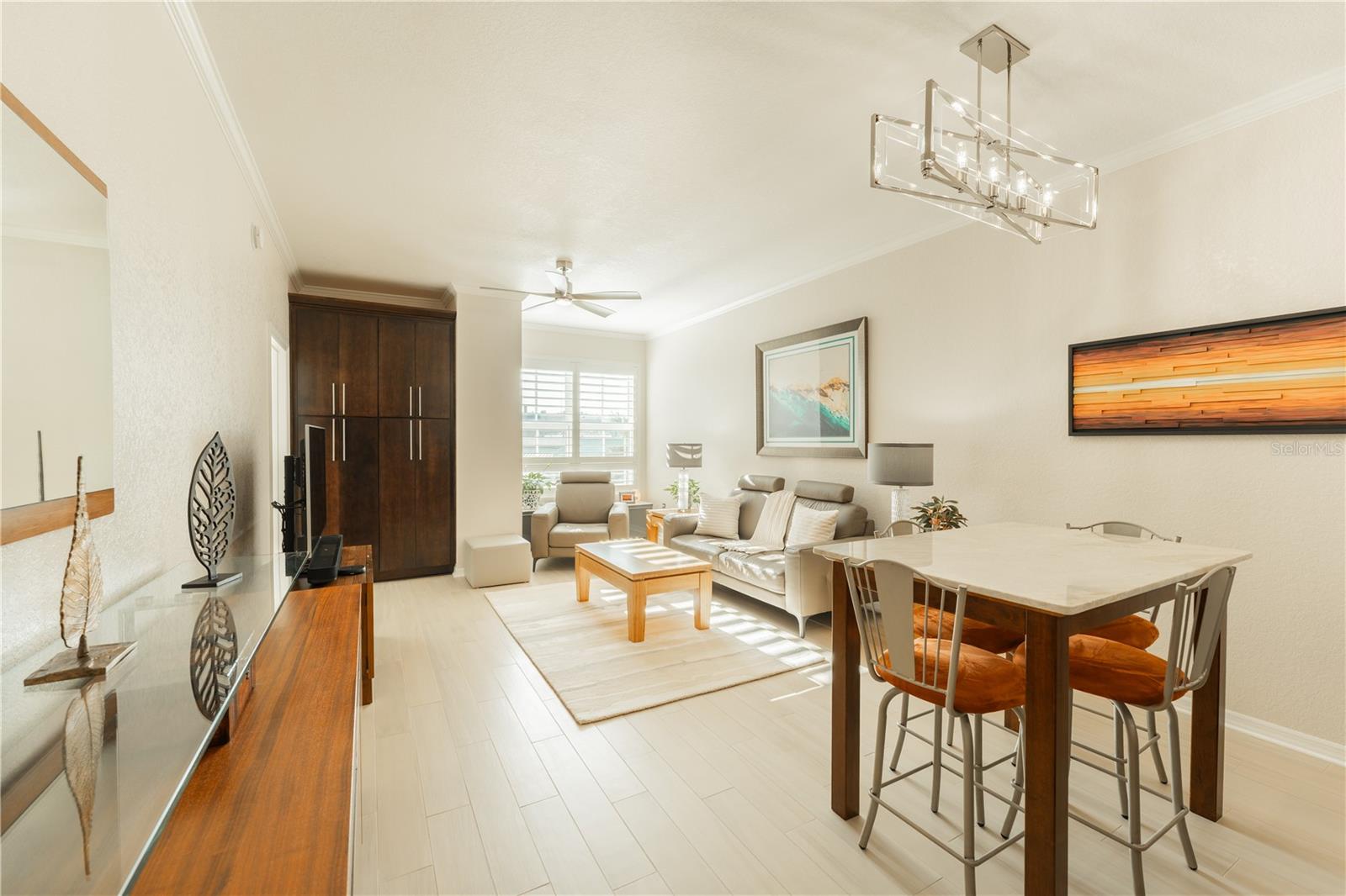 The living and dining area, adorned with custom storage cabinets, elegant porcelain tile floors, and impressive high ceilings, offers a welcoming ambiance ideal for both relaxation and entertaining.