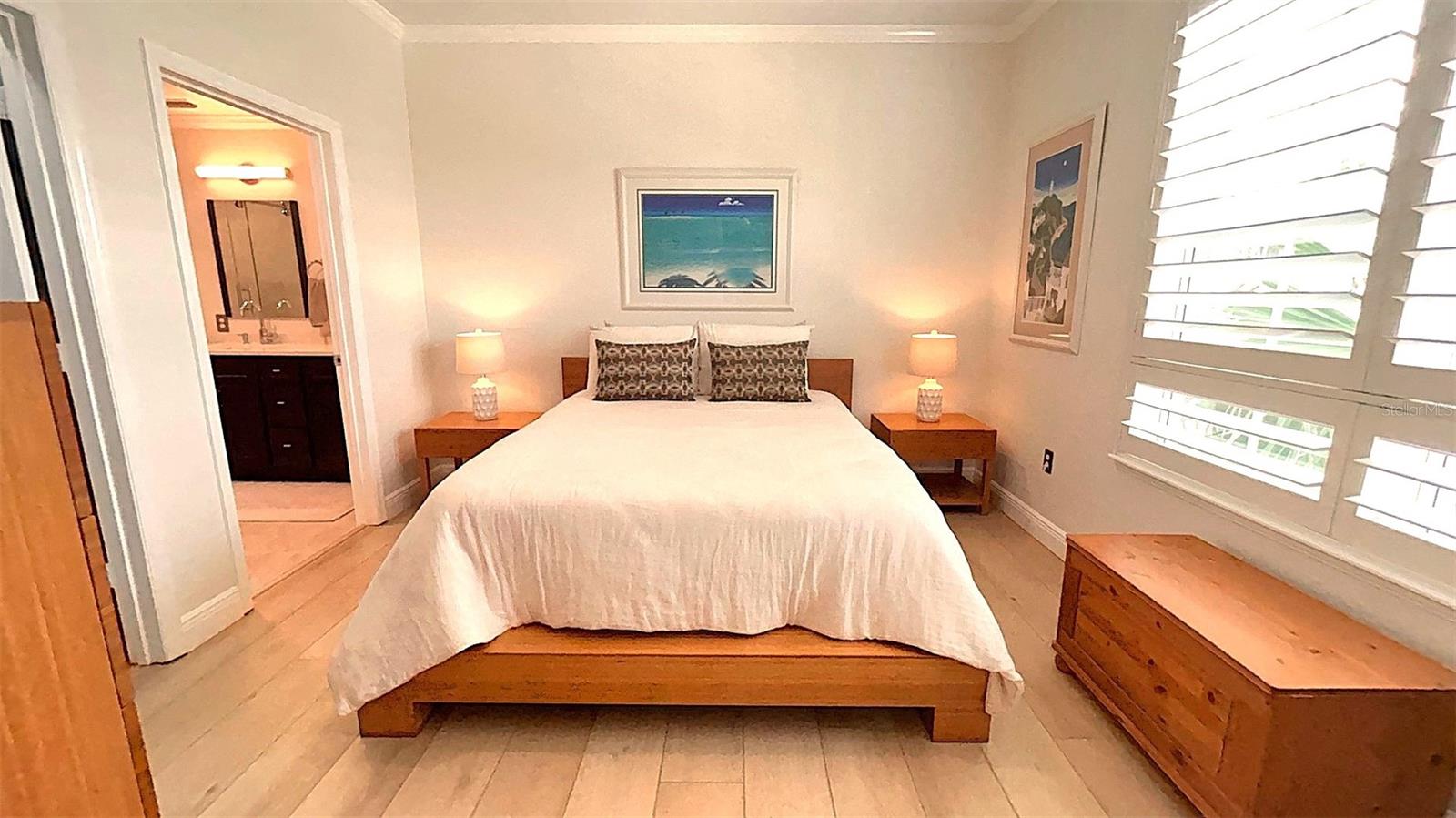 The primary bedroom boasts new windows, elegant shutters, LVP flooring, and stylish bamboo furniture, creating a warm and inviting retreat.