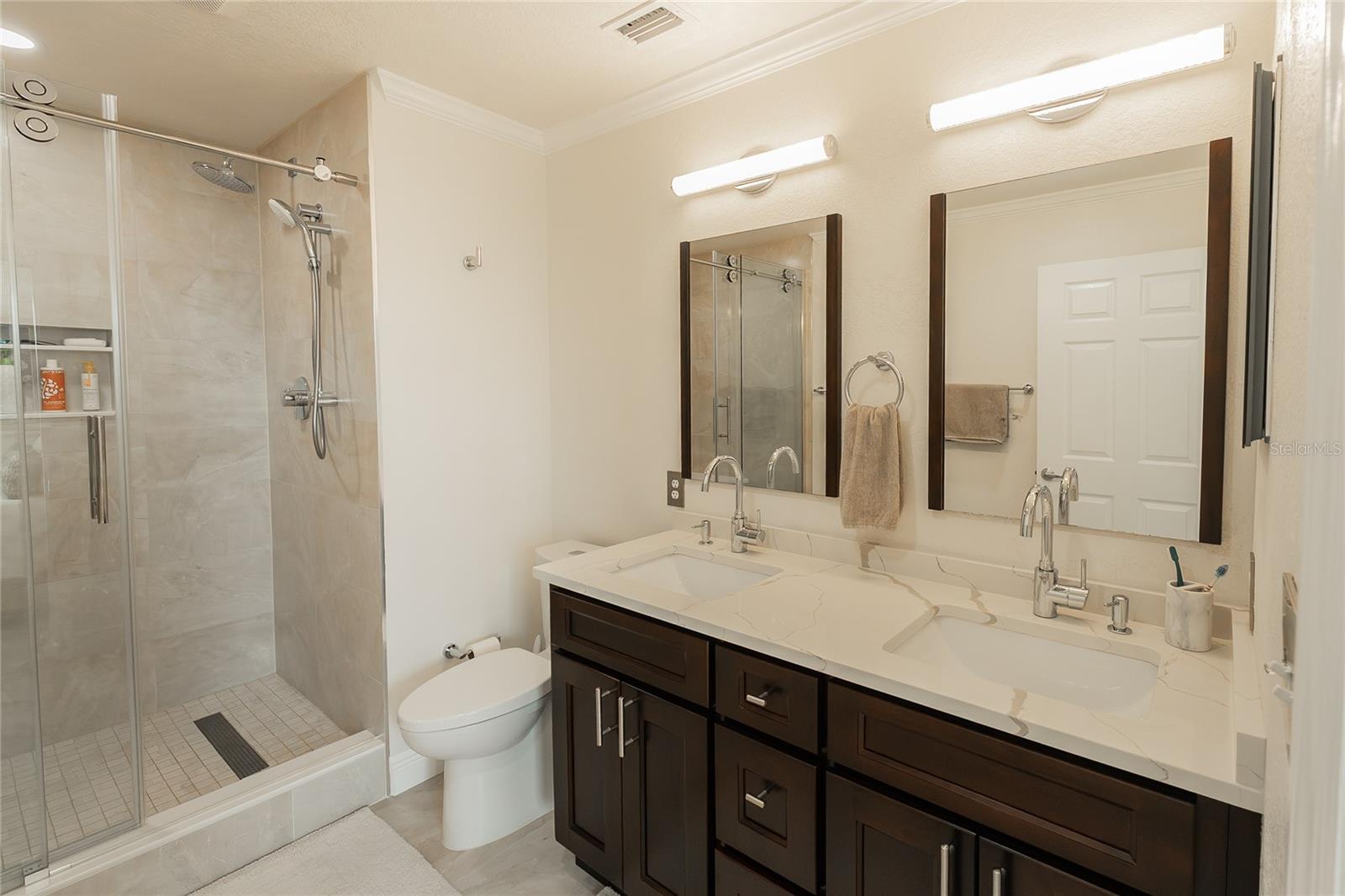 A double vanity showcases a gorgeous quartz countertop, beautifully enhanced by sparkling crystal lighting for an elegant touch.