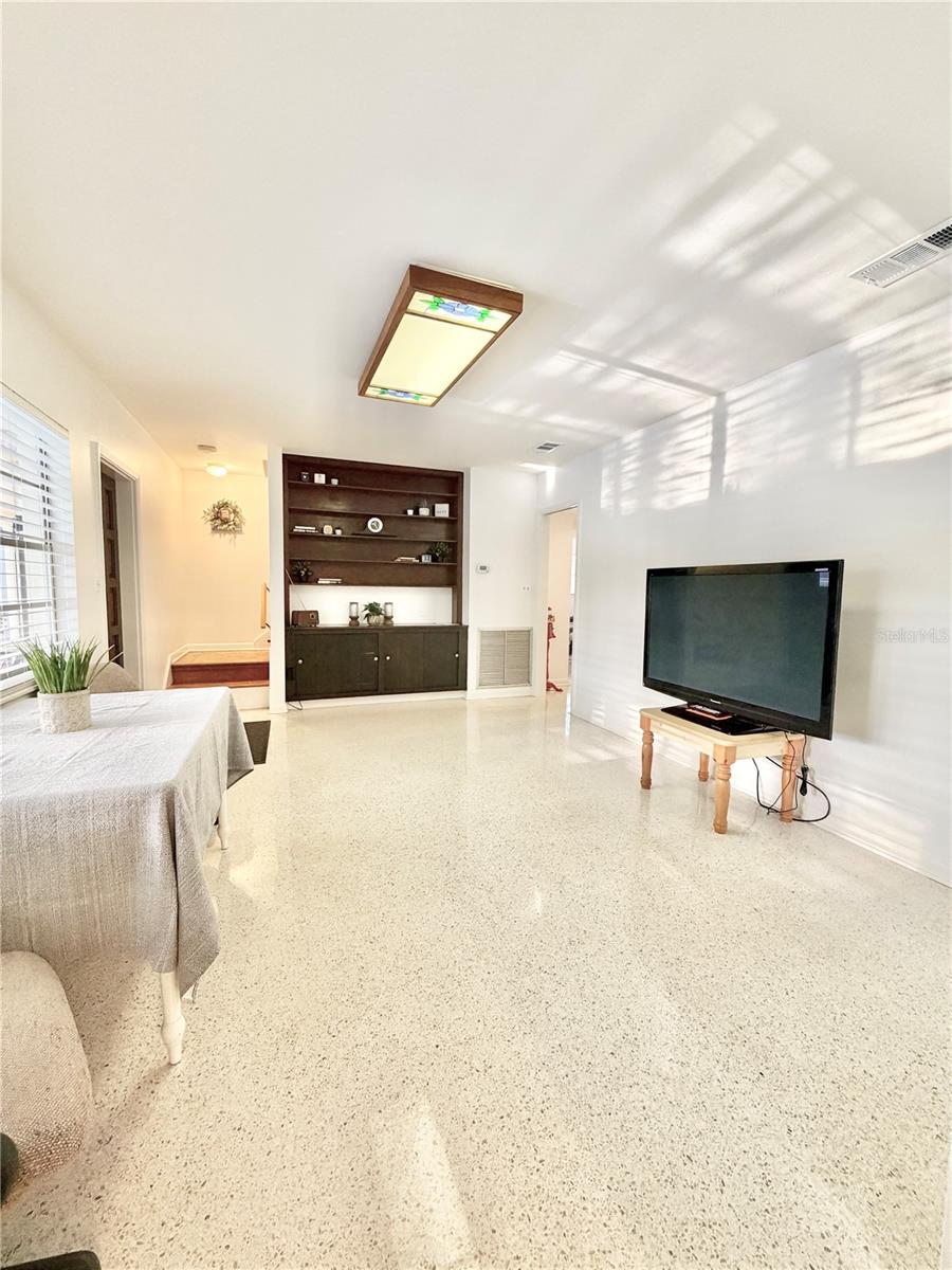 Living Room has built-in shelving and overlooks the pool through a large window.