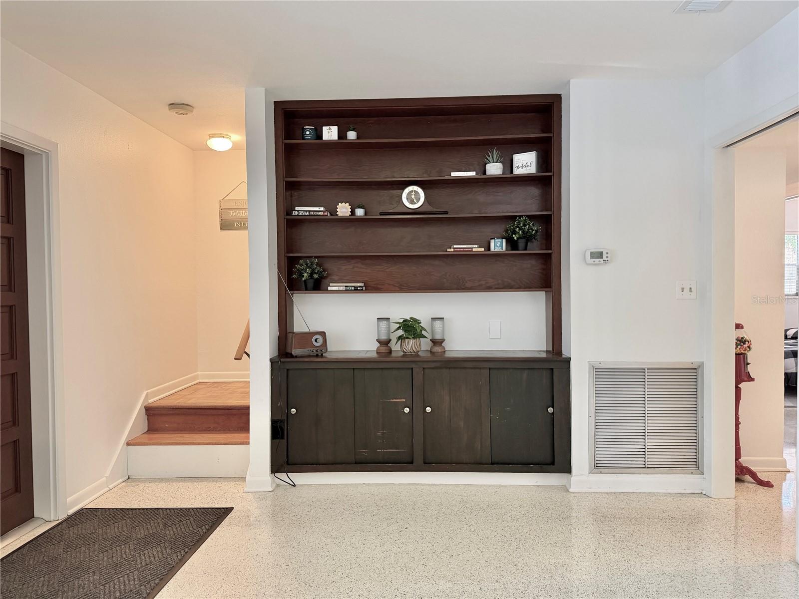 Living Room has built-in shelving and overlooks the pool through a large window.